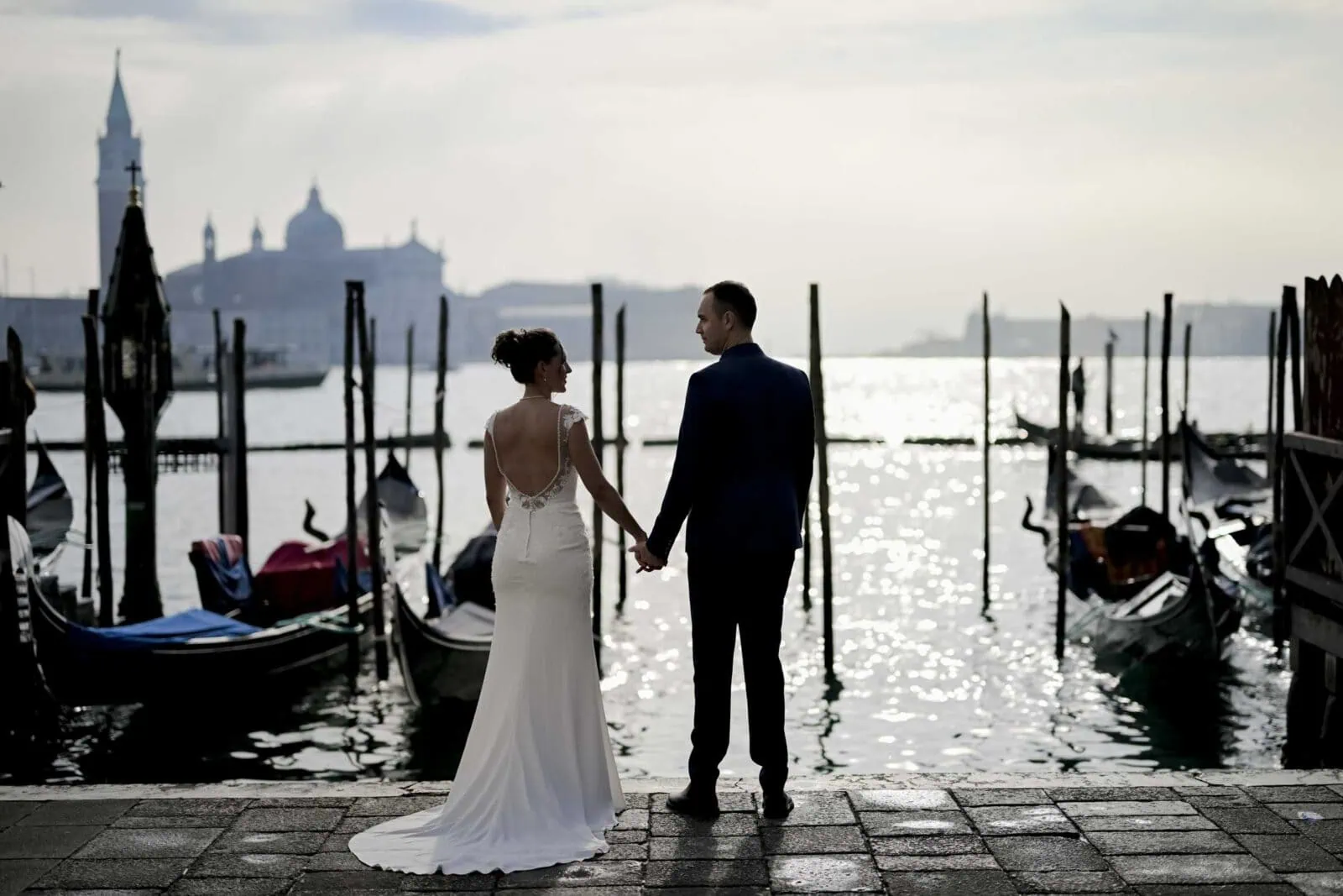 Romantic couple enjoying their honeymoon in Venice, Italy, captured in a scenic Venetian backdrop with historic canals, gondolas, and iconic landmarks.