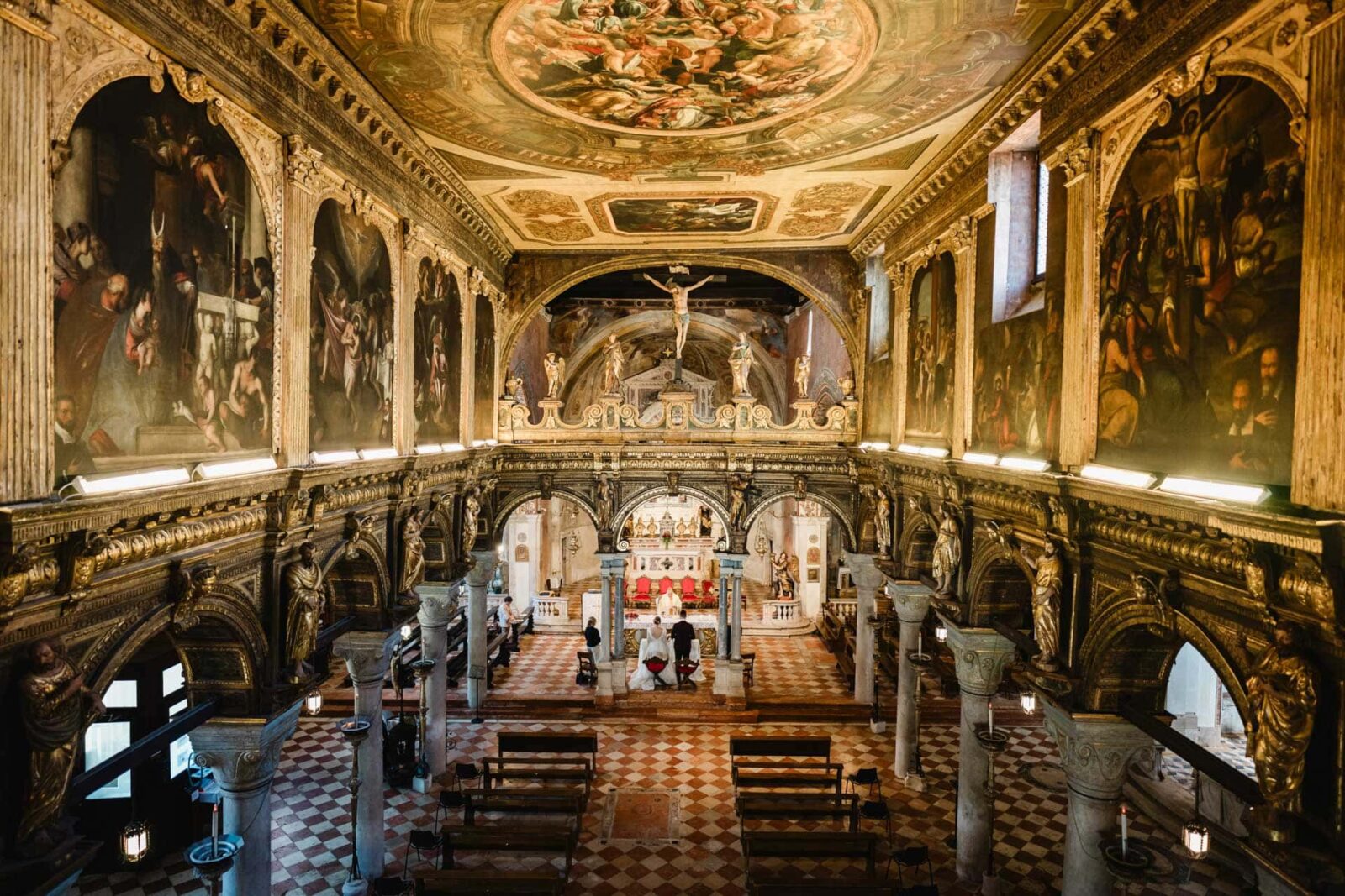 Magnificent Venetian church interior with ornate gold accents, frescoes, and religious statues.