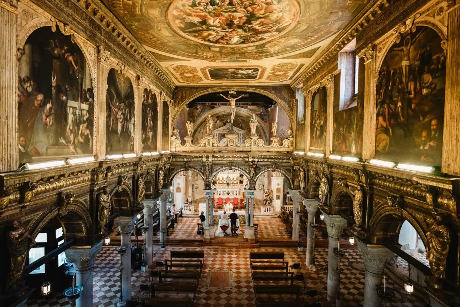 Magnificent Venetian church interior with ornate gold accents, frescoes, and religious statues.