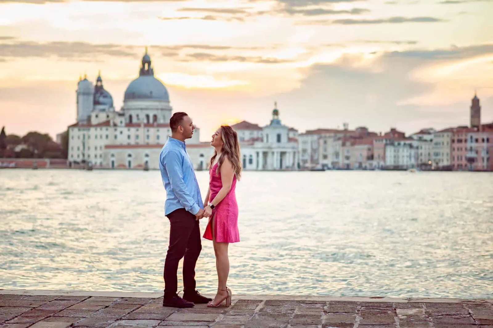 Engagement photos in Venice with a couple embracing by the Grand Canal at sunset.