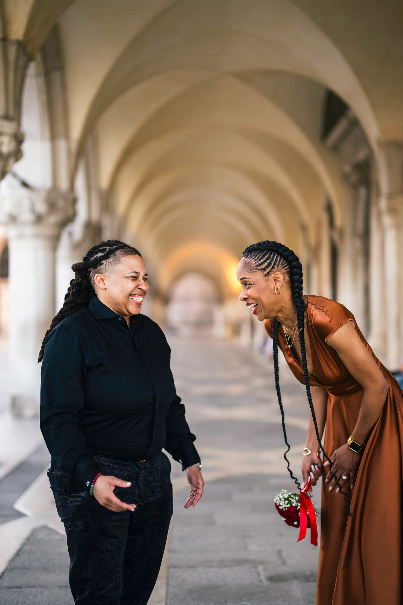 Two women in love under the arcades of San Marco with Bridge of Sighs behind them