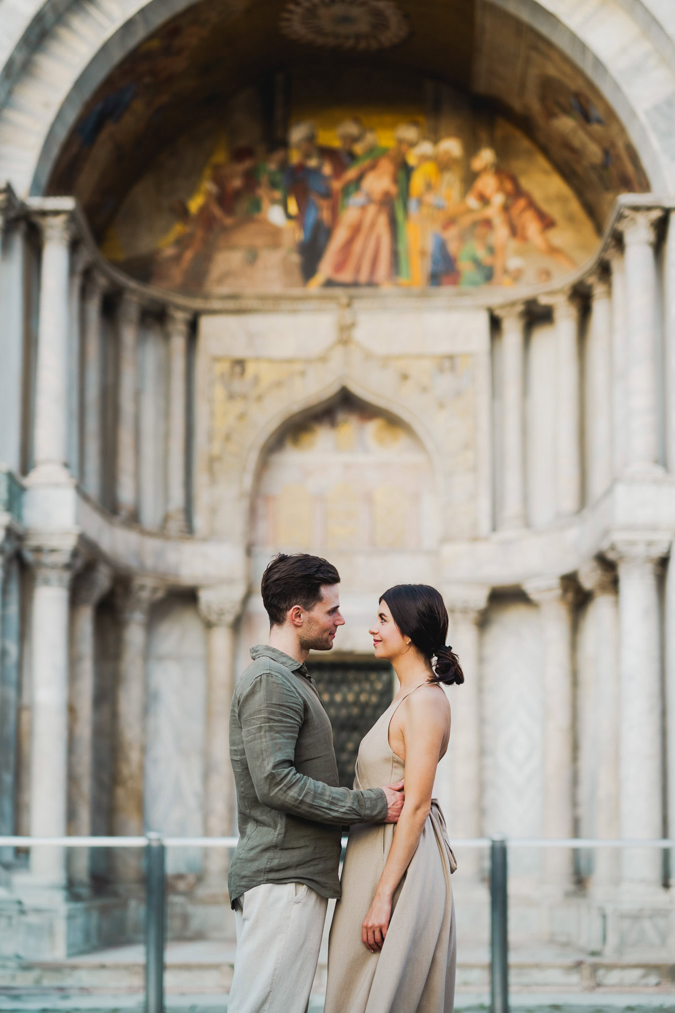 Engaged couple standing under the historic arches of San Marco