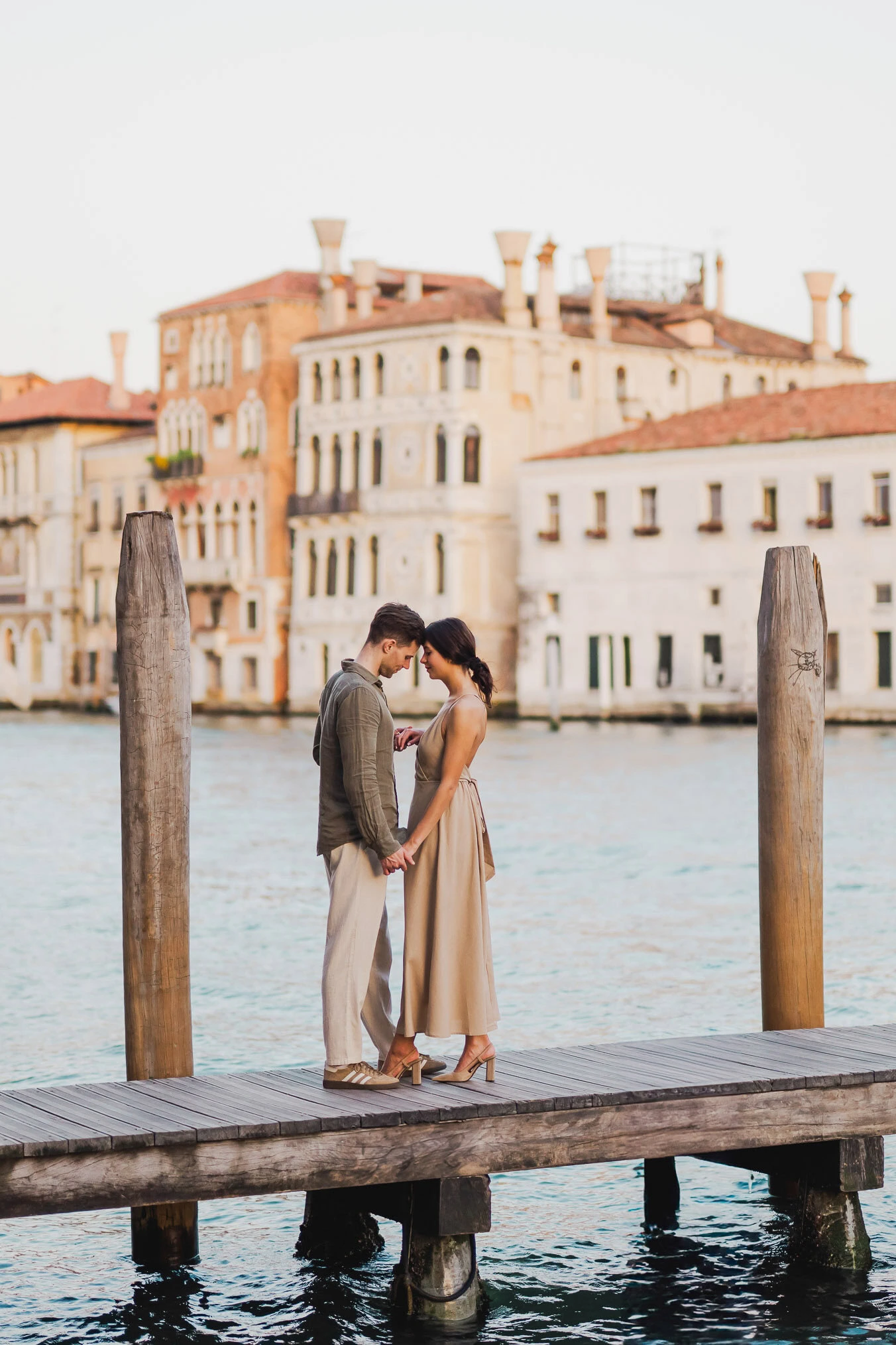 Couple sitting beside a Venetian canal during engagement shoot