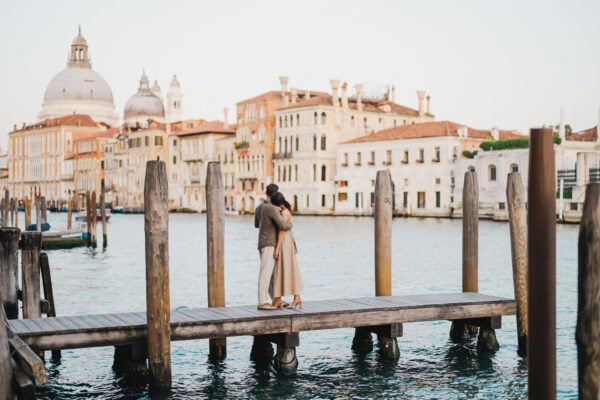 Couple sitting beside a Venetian canal during engagement shoot