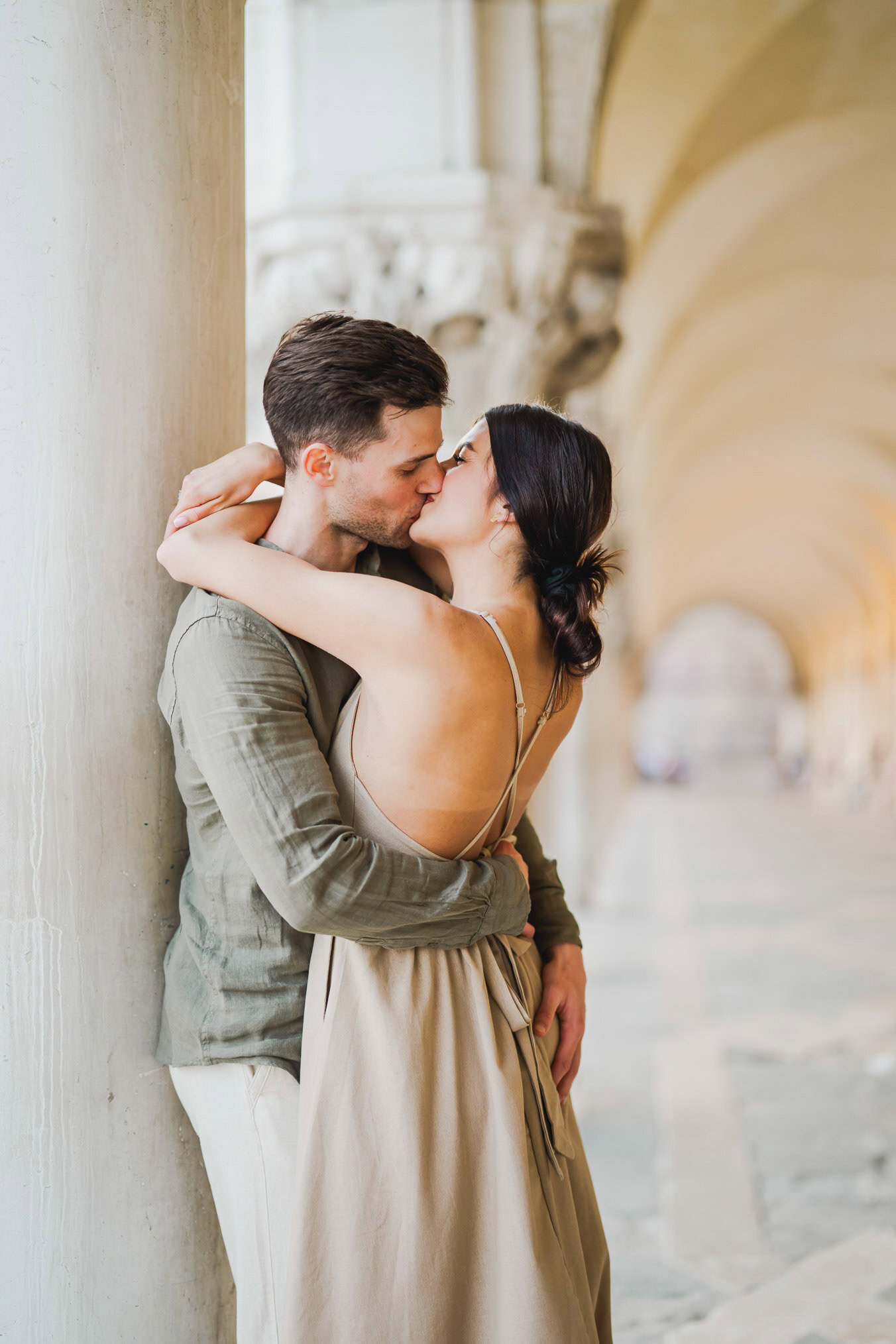 Engaged couple standing under the historic arches of San Marco