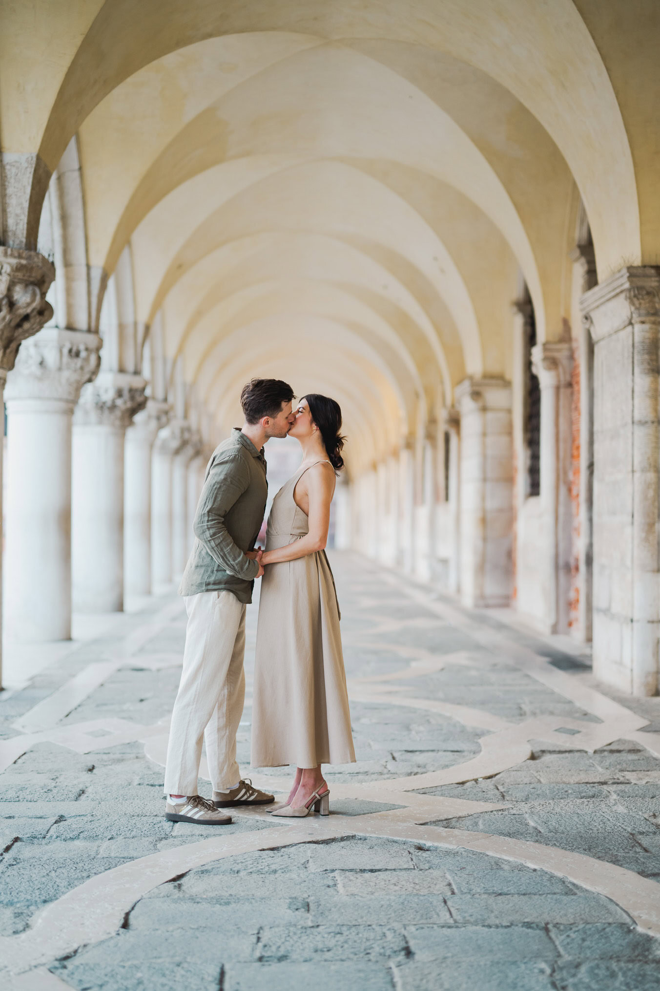 Engaged couple standing under the historic arches of San Marco