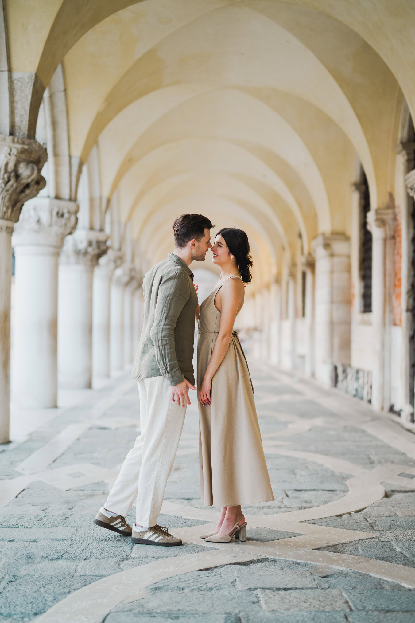 Engaged couple standing under the historic arches of San Marco
