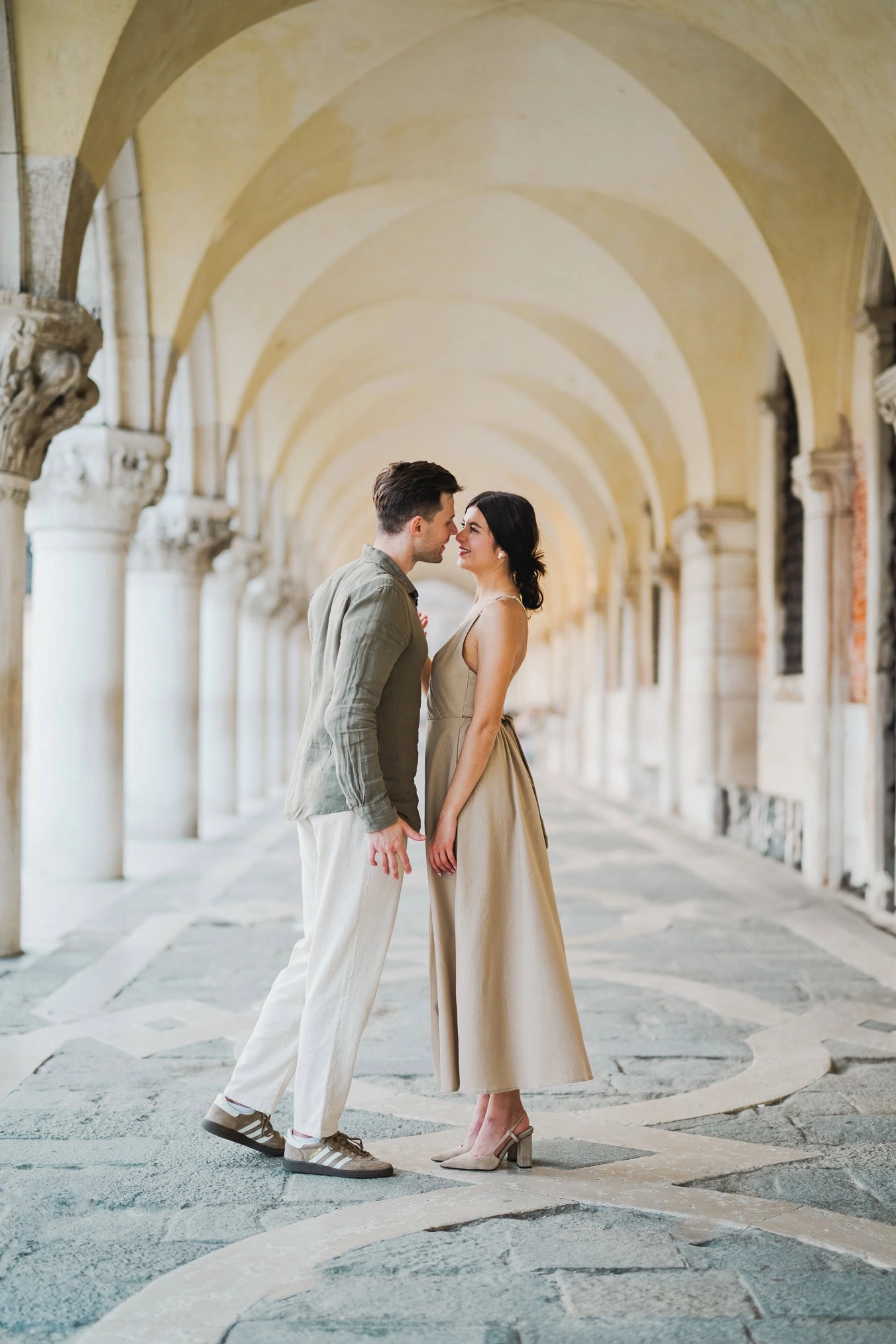 Engaged couple standing under the historic arches of San Marco