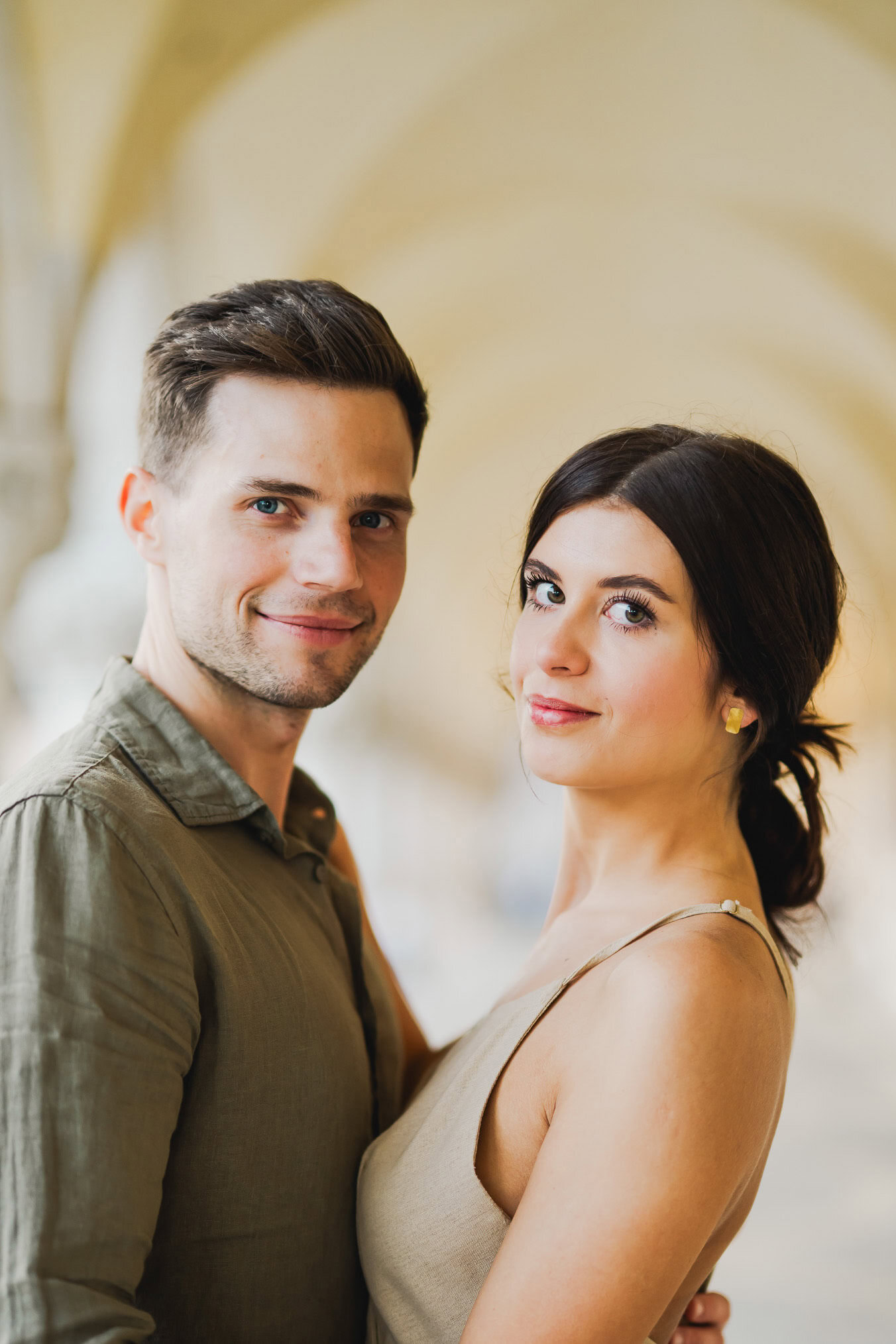 Engaged couple standing under the historic arches of San Marco
