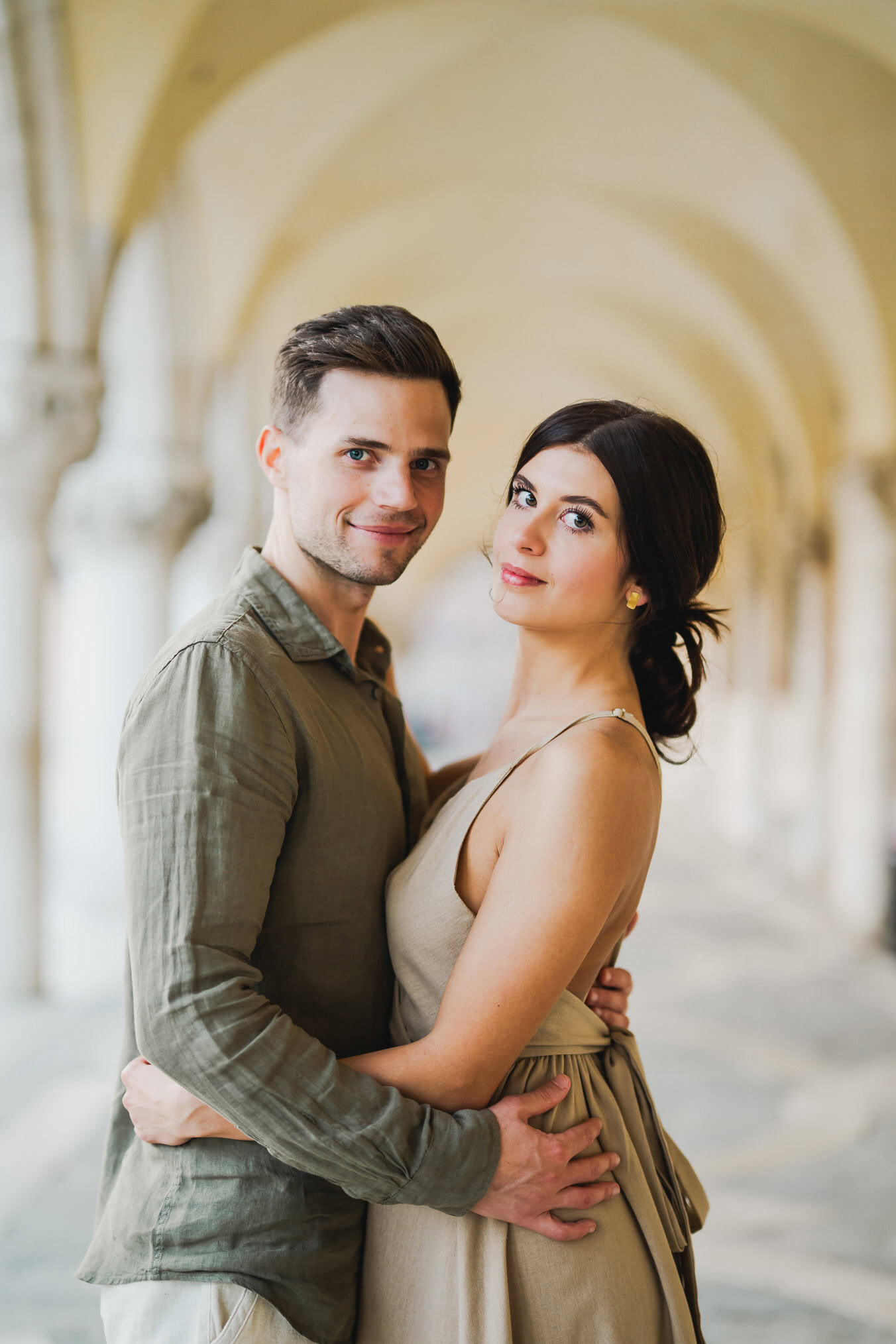 Engaged couple standing under the historic arches of San Marco