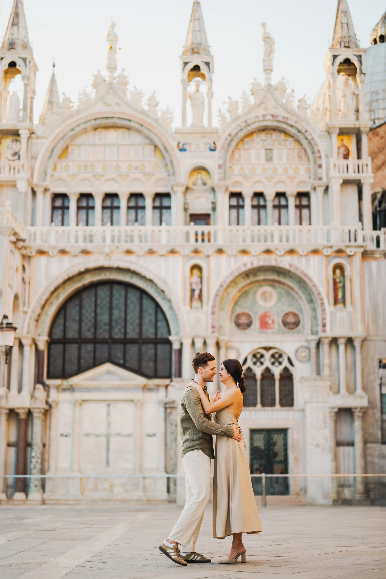 Engaged couple standing under the historic arches of San Marco