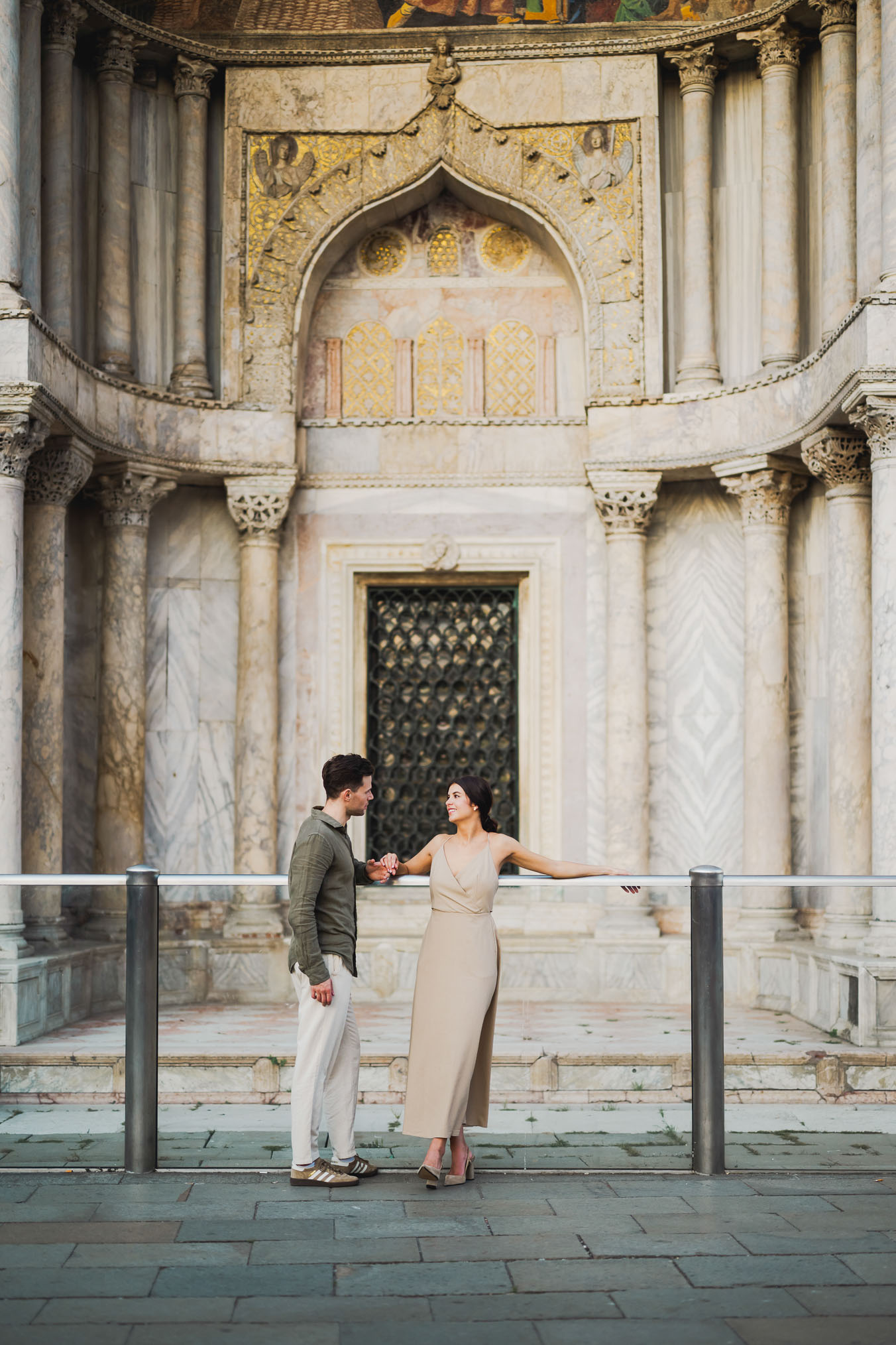 Engaged couple standing under the historic arches of San Marco