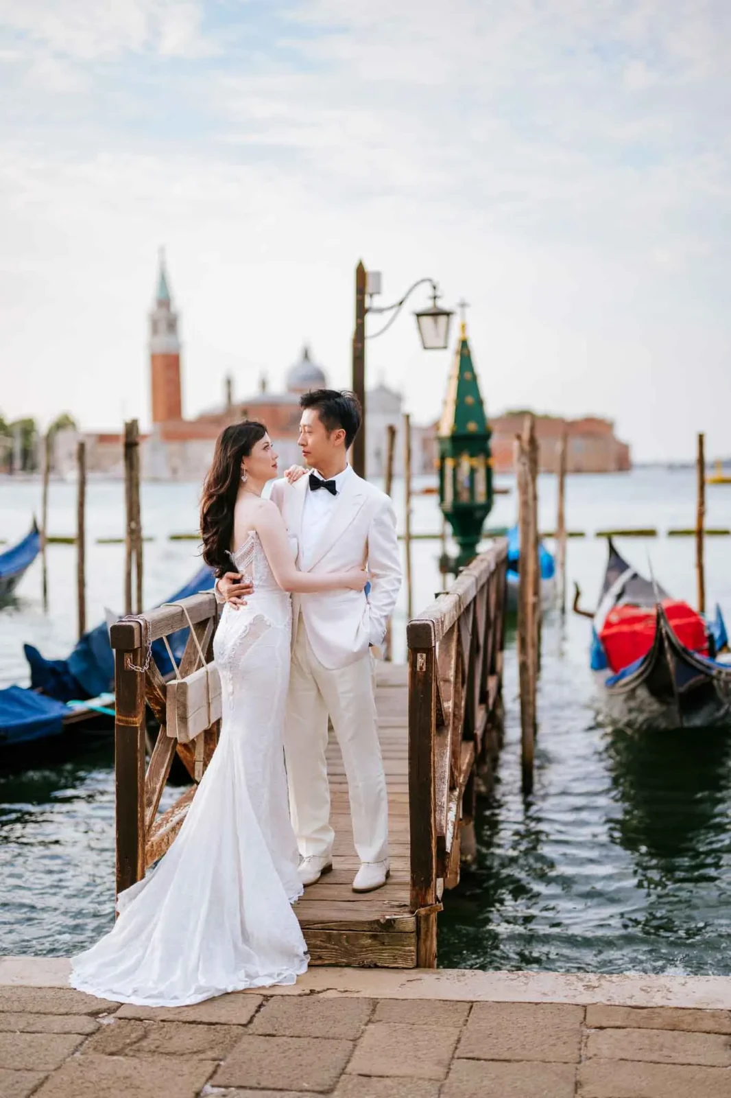 Elegant wedding couple in Venice by the water with gondolas and historic architecture in the background, perfect for wedding and engagement shoots.