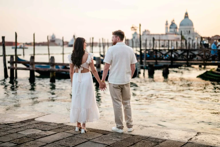 Romantic couple holding hands by Venice canal, sunset sky, historic architecture, wedding proposal, engagement photos.