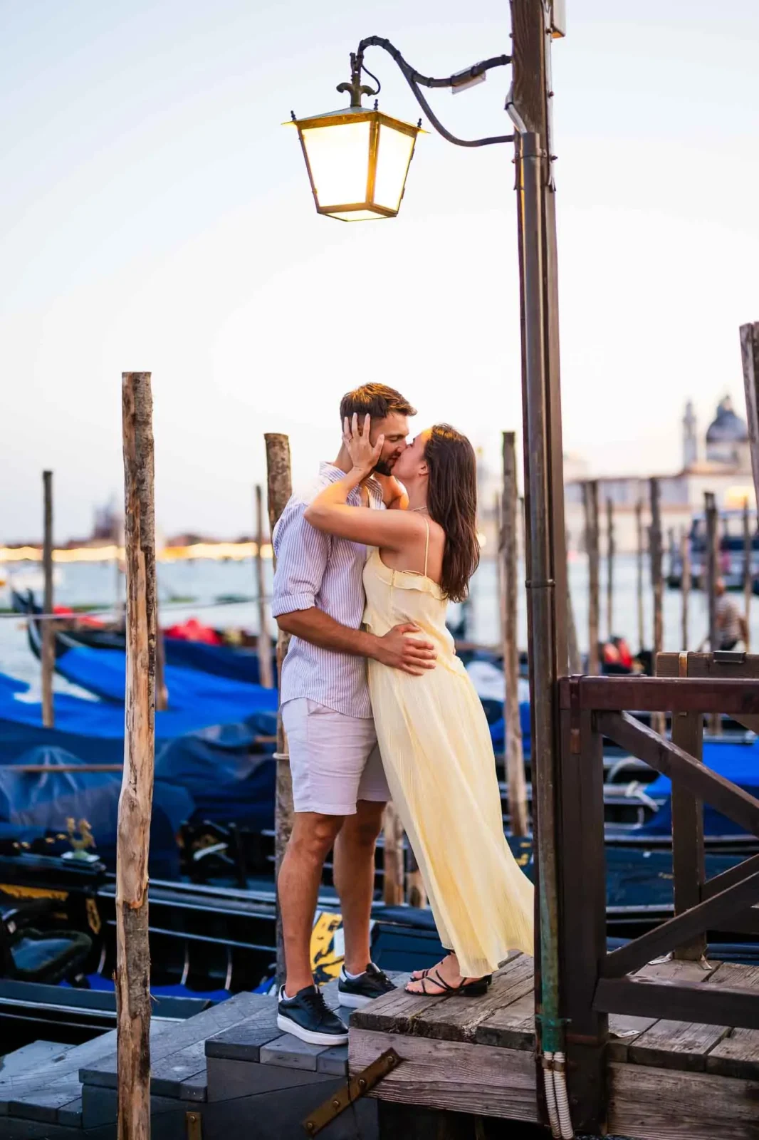 1. Romantic couple kissing at Venice gondola docks during sunset, celebrating love and engagement.