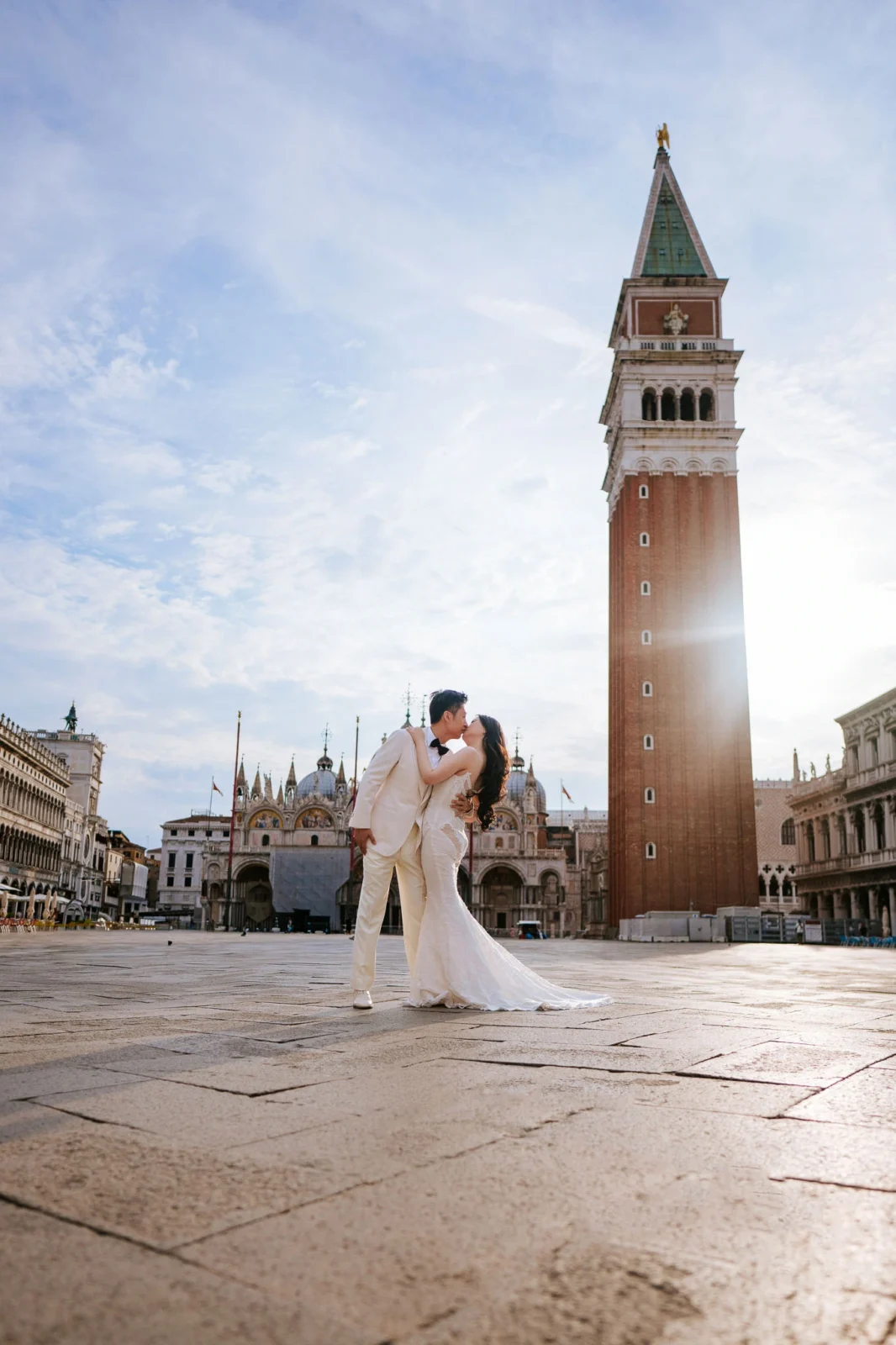 Elegant bride and groom kissing in St. Mark's Square, Venice, during their wedding celebration.