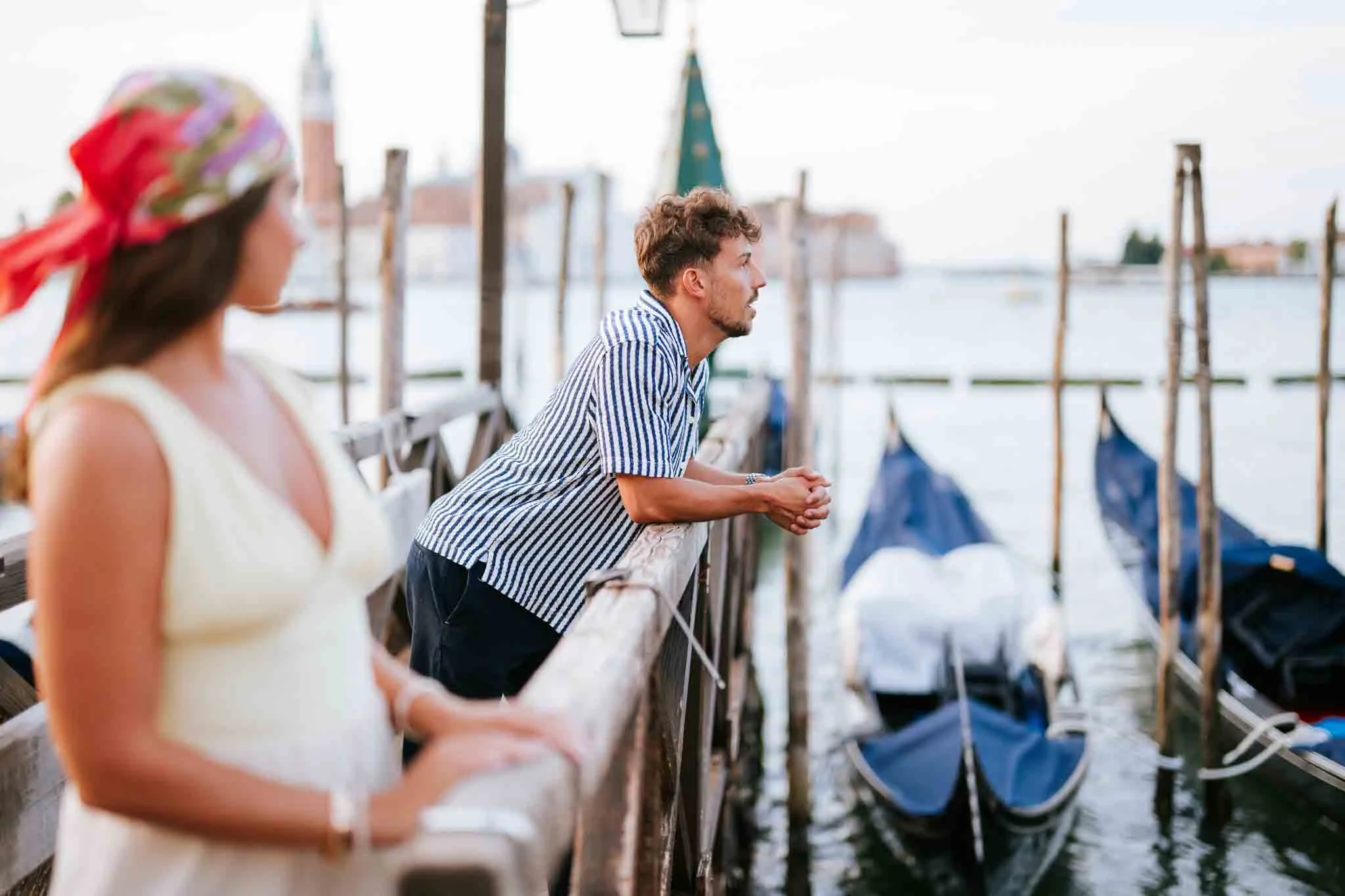 Romantic Venice couple by the water on a gondola dock, capturing engagement moments in Italy.
