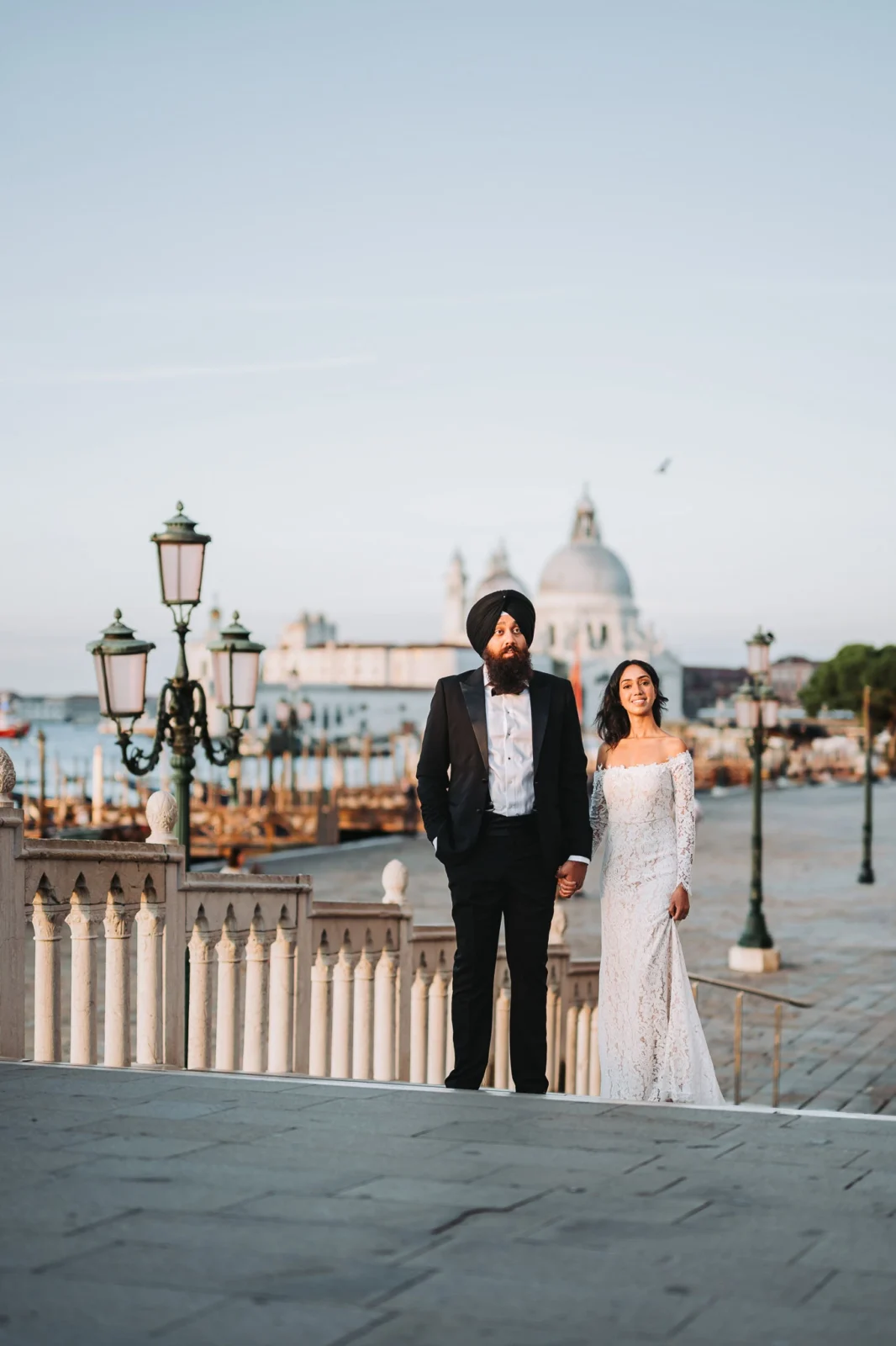 Elegant wedding couple holding hands in Venice, with iconic canals and architecture in the background.