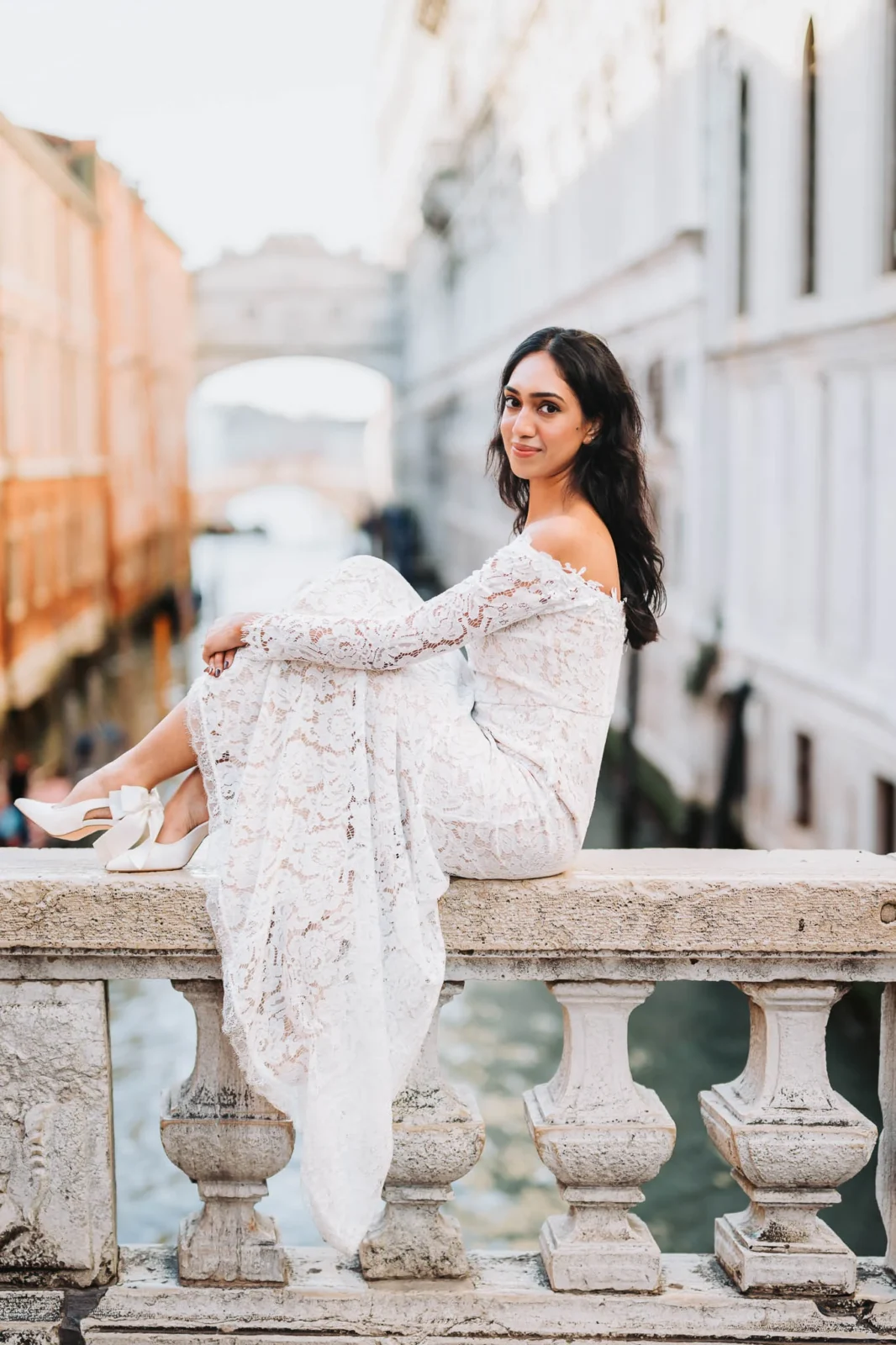 1. Beautiful woman in white lace dress sitting on a Venice bridge.