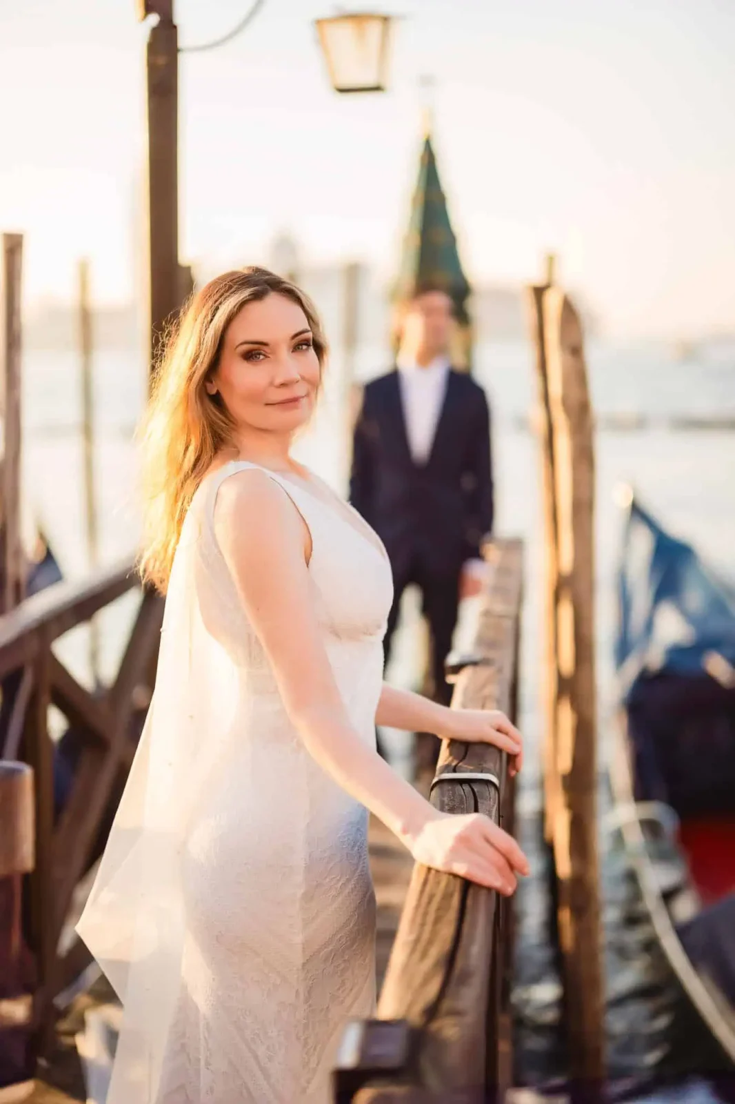 Elegant bride on a Venice dock during sunset, capturing romantic wedding moments in Italy.