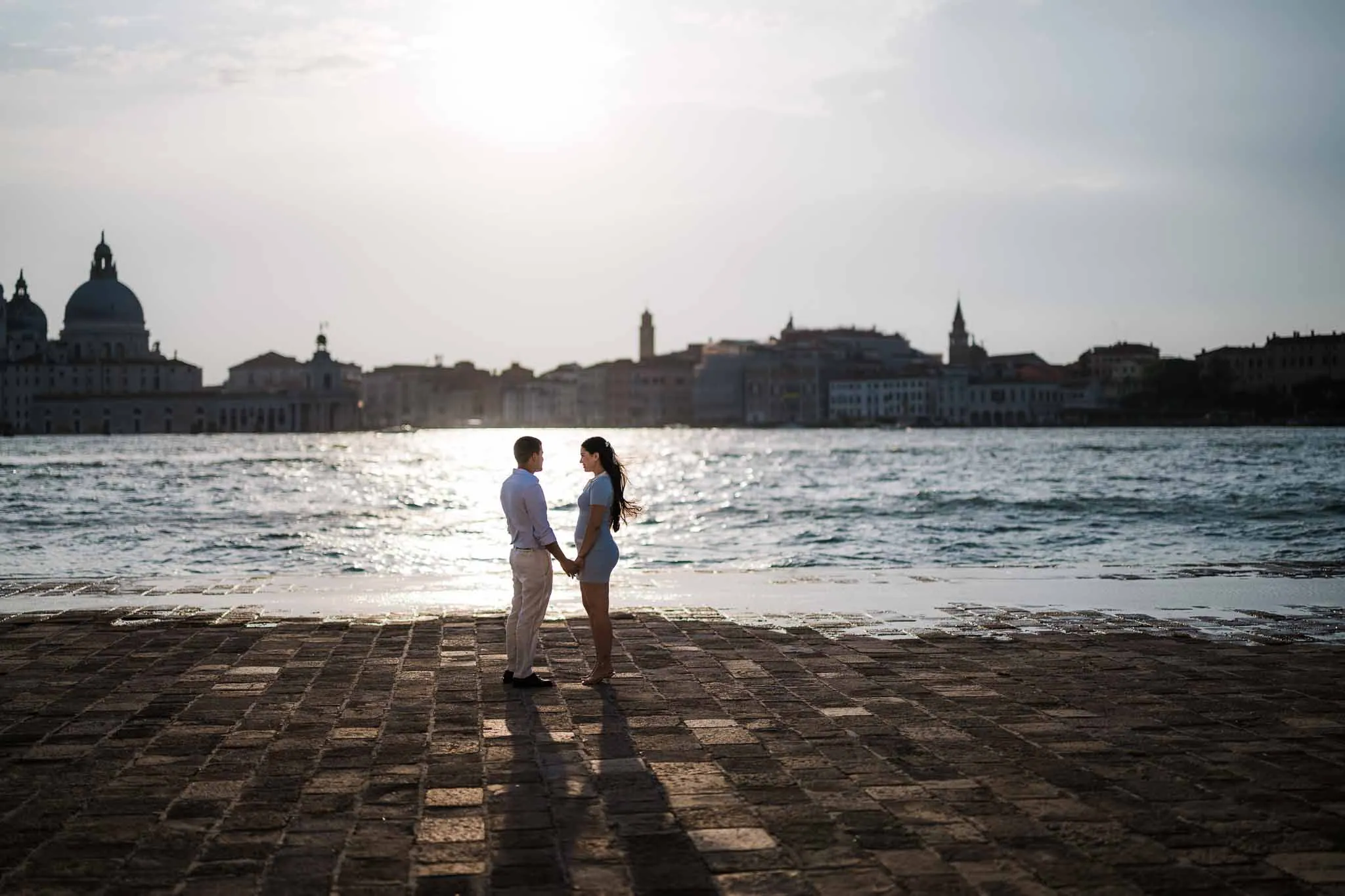 Couple holding hands by water.