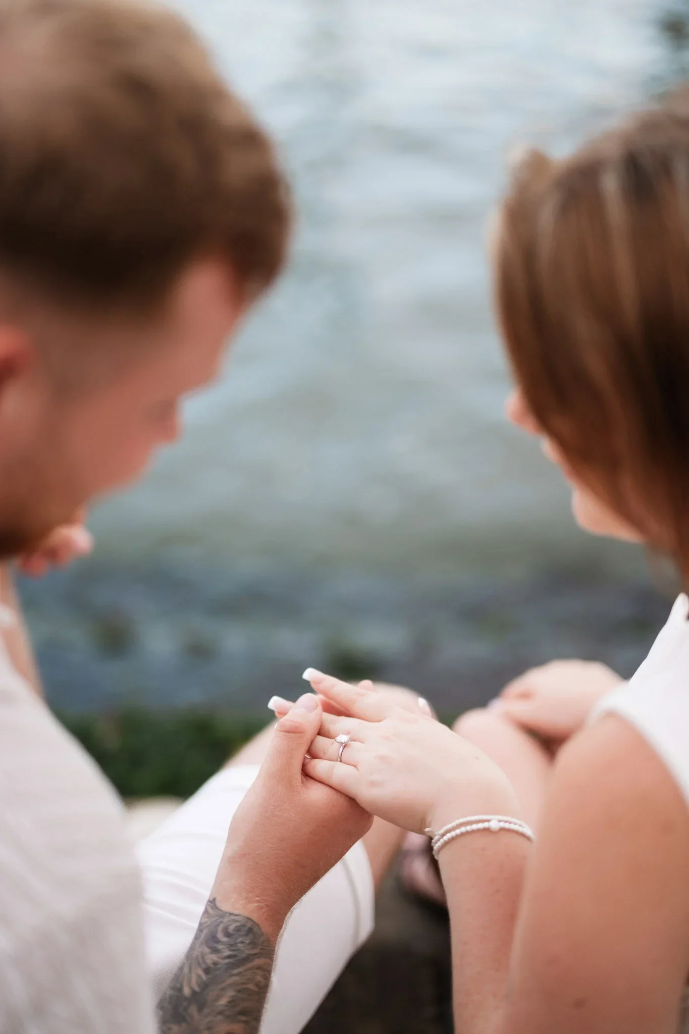 Couple holding hands by water.