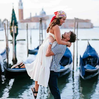 Couple embracing near gondolas in Venice.