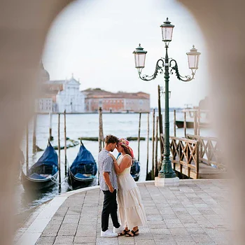 Couple kissing near Venetian waterfront.