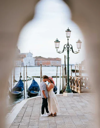 Couple kissing near Venetian waterfront.