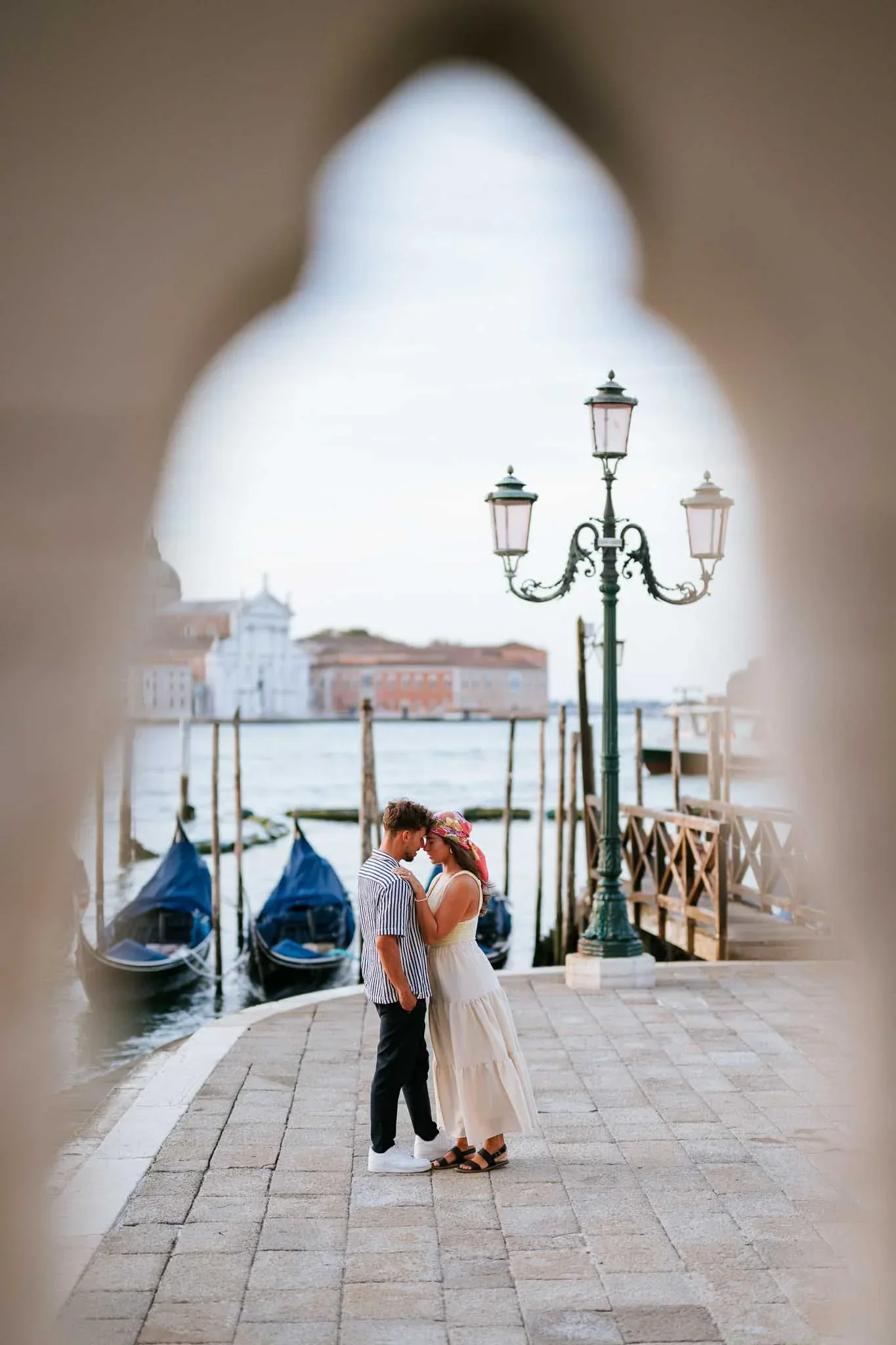 Couple kissing near Venetian waterfront.