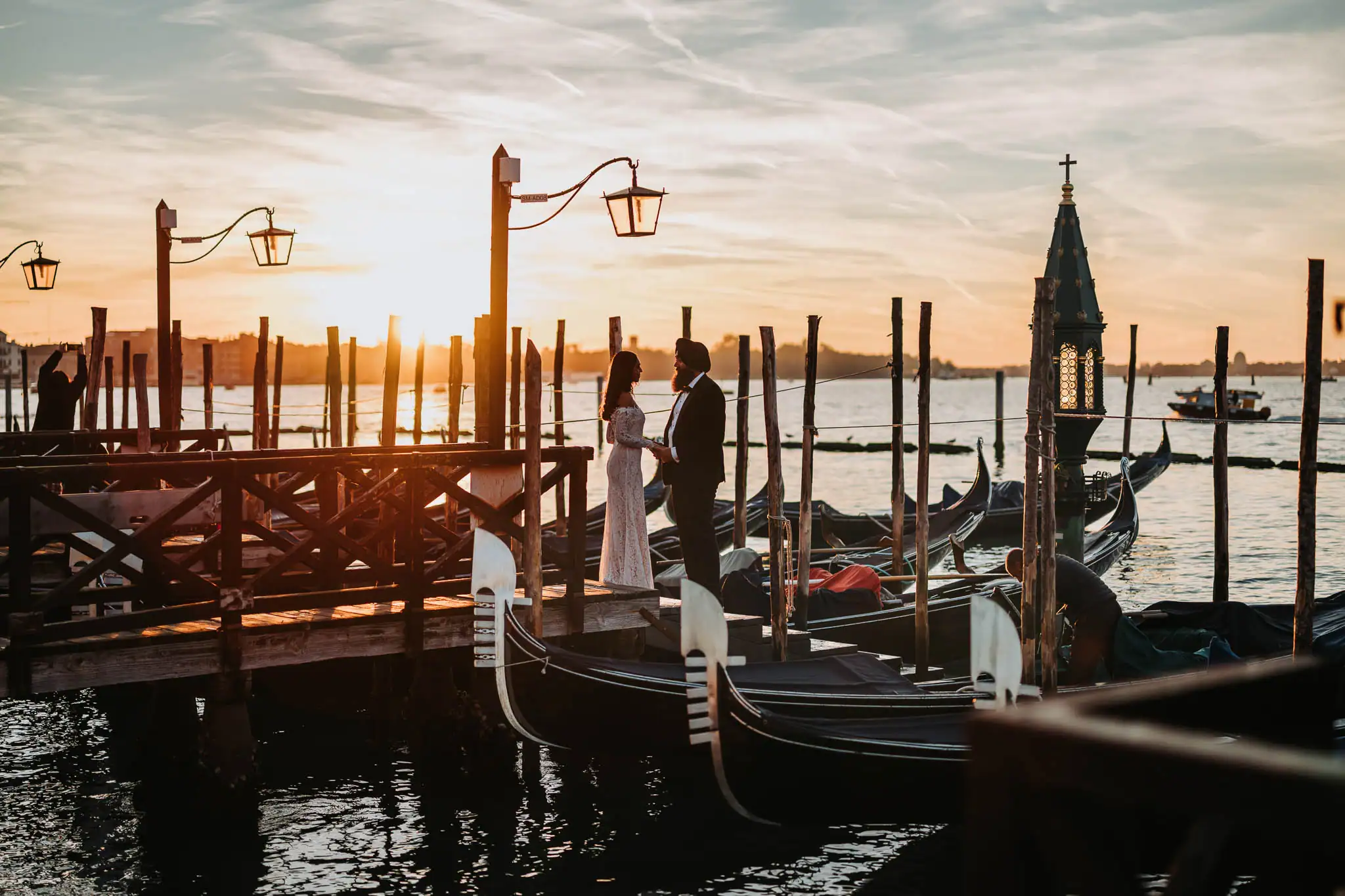 Couple at sunset by gondolas.