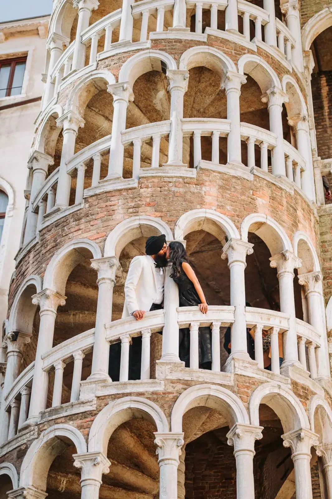 1. Romantic couple sharing kiss on historic Venetian balcony at sunset.