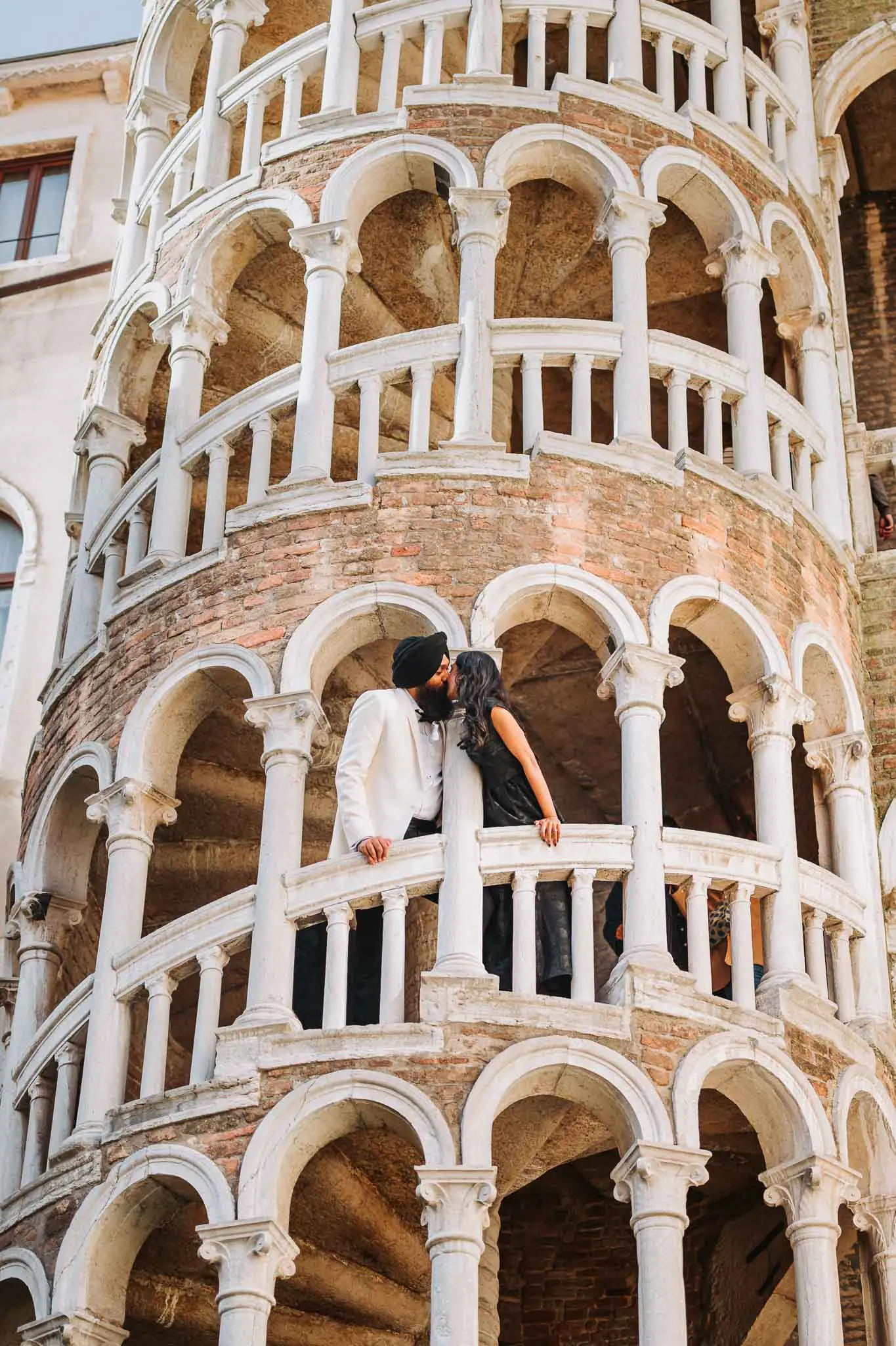 1. Romantic couple sharing kiss on historic Venetian balcony at sunset.