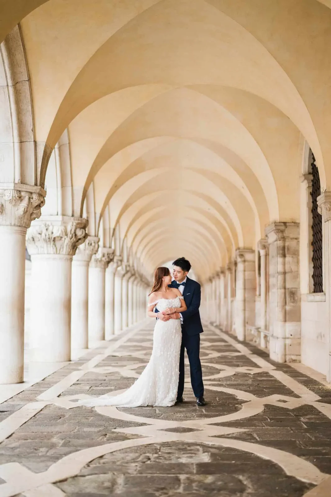 Elegant wedding couple in historic Venetian arcade.