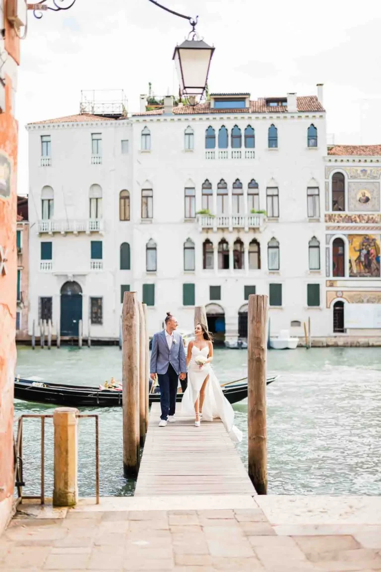 Romantic Venice wedding couple walking on dock by canal.