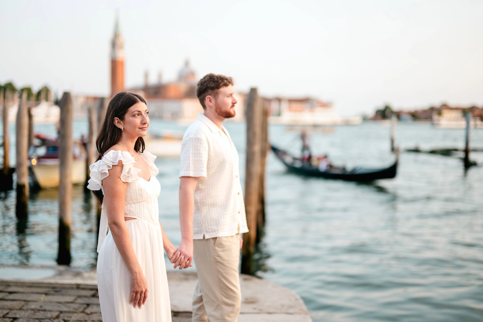 Romantic Venice couple holding hands by the water during a wedding or engagement photoshoot.
