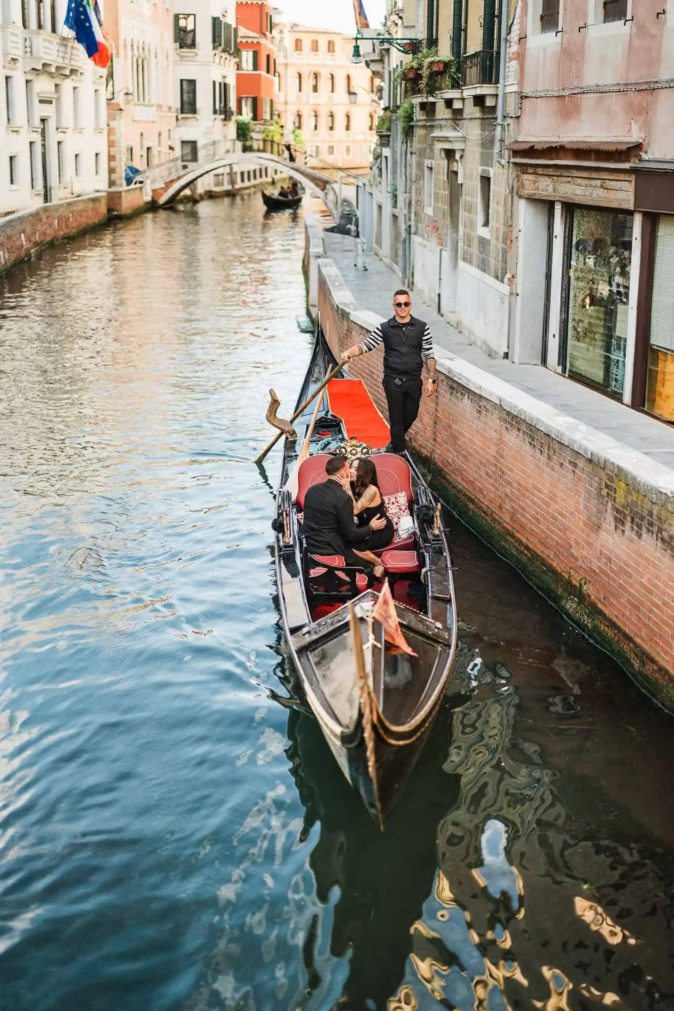 1. Romantic Venice gondola ride with couple and gondolier near historic buildings.