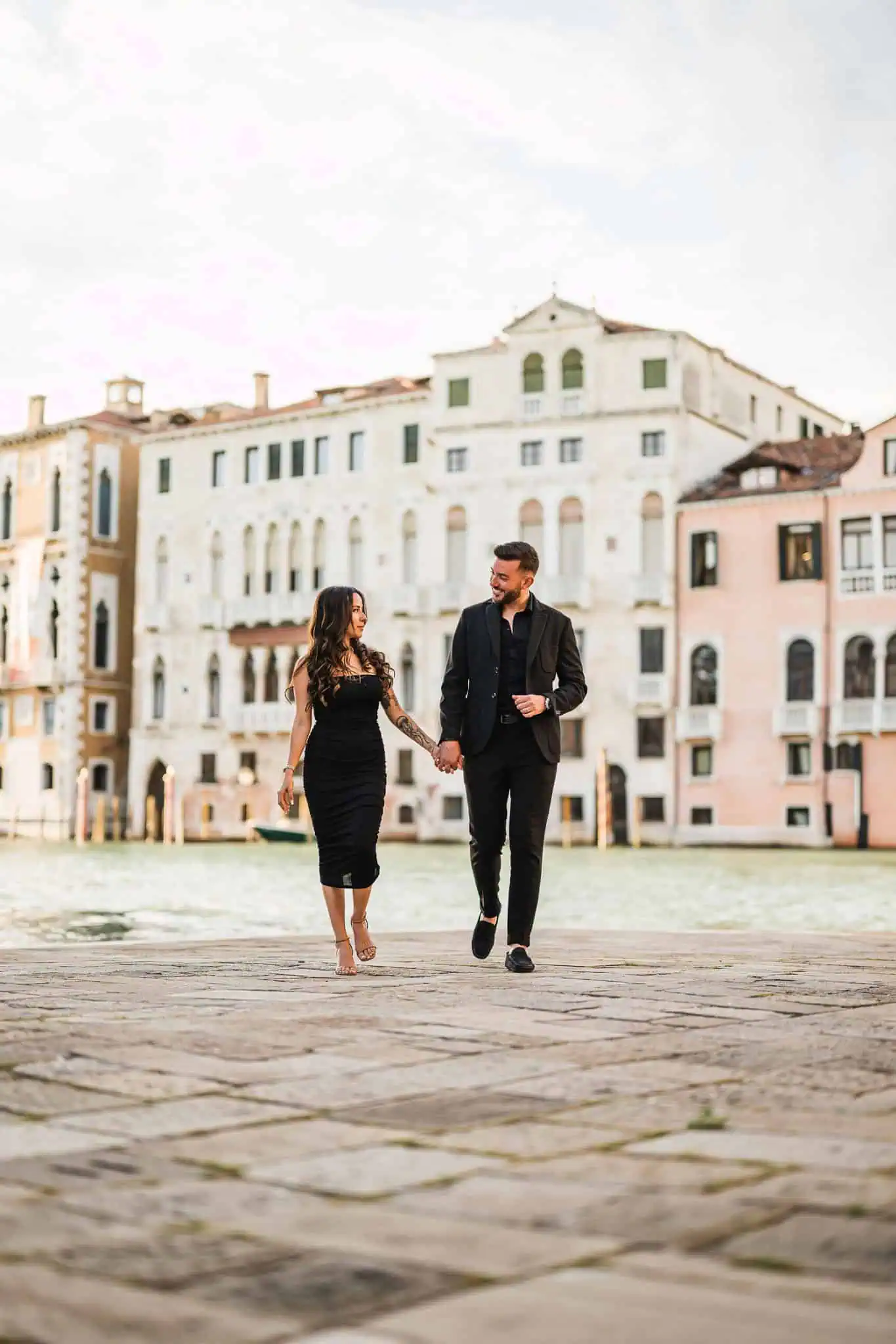 Elegant couple holding hands in Venice, best engagement photographer, romantic cityscape backdrop.