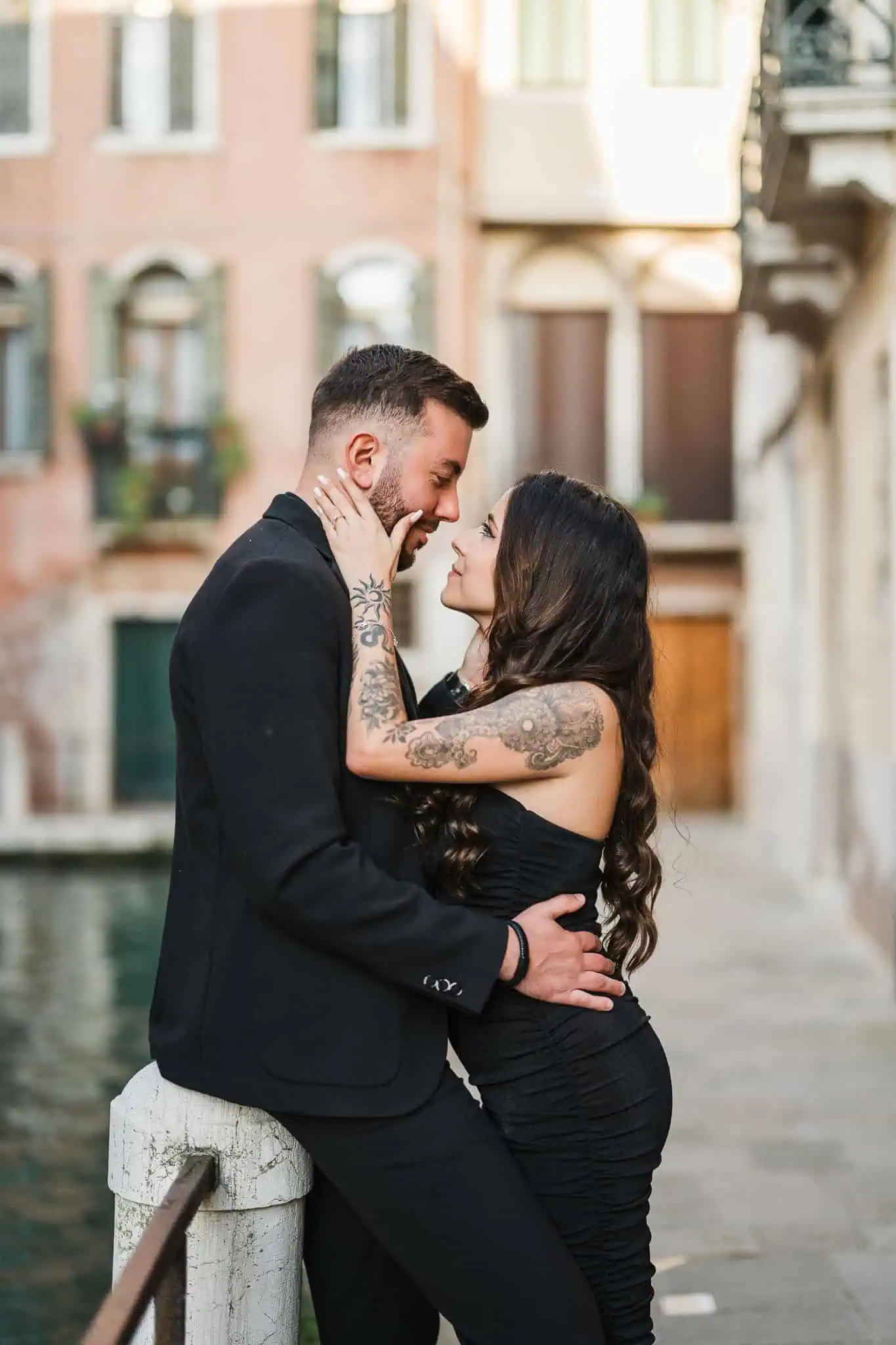 Intimate Venice engagement photo of a tattooed couple close together by a canal.