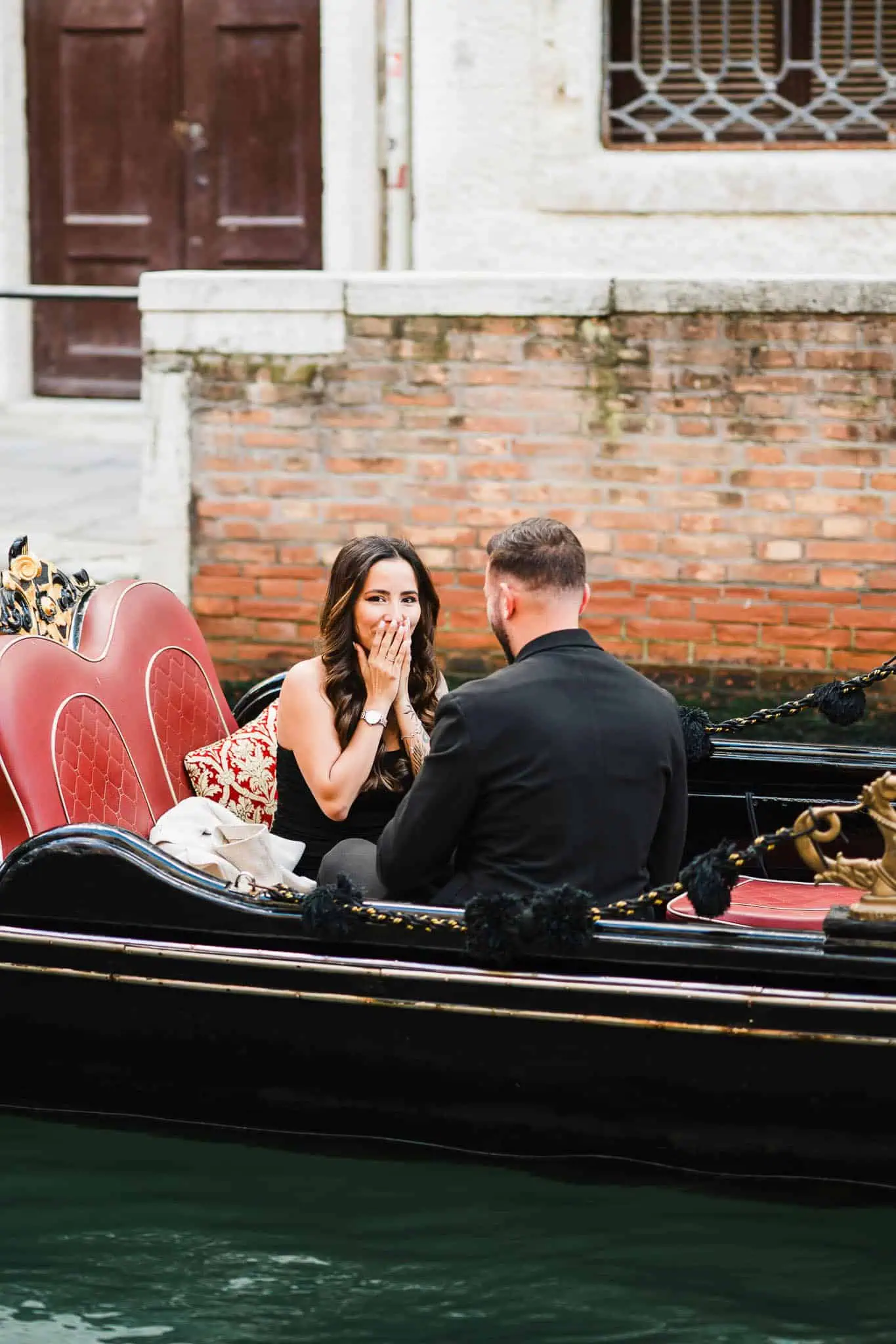 Romantic Venice gondola proposal with joyful woman and man, cityscape background.