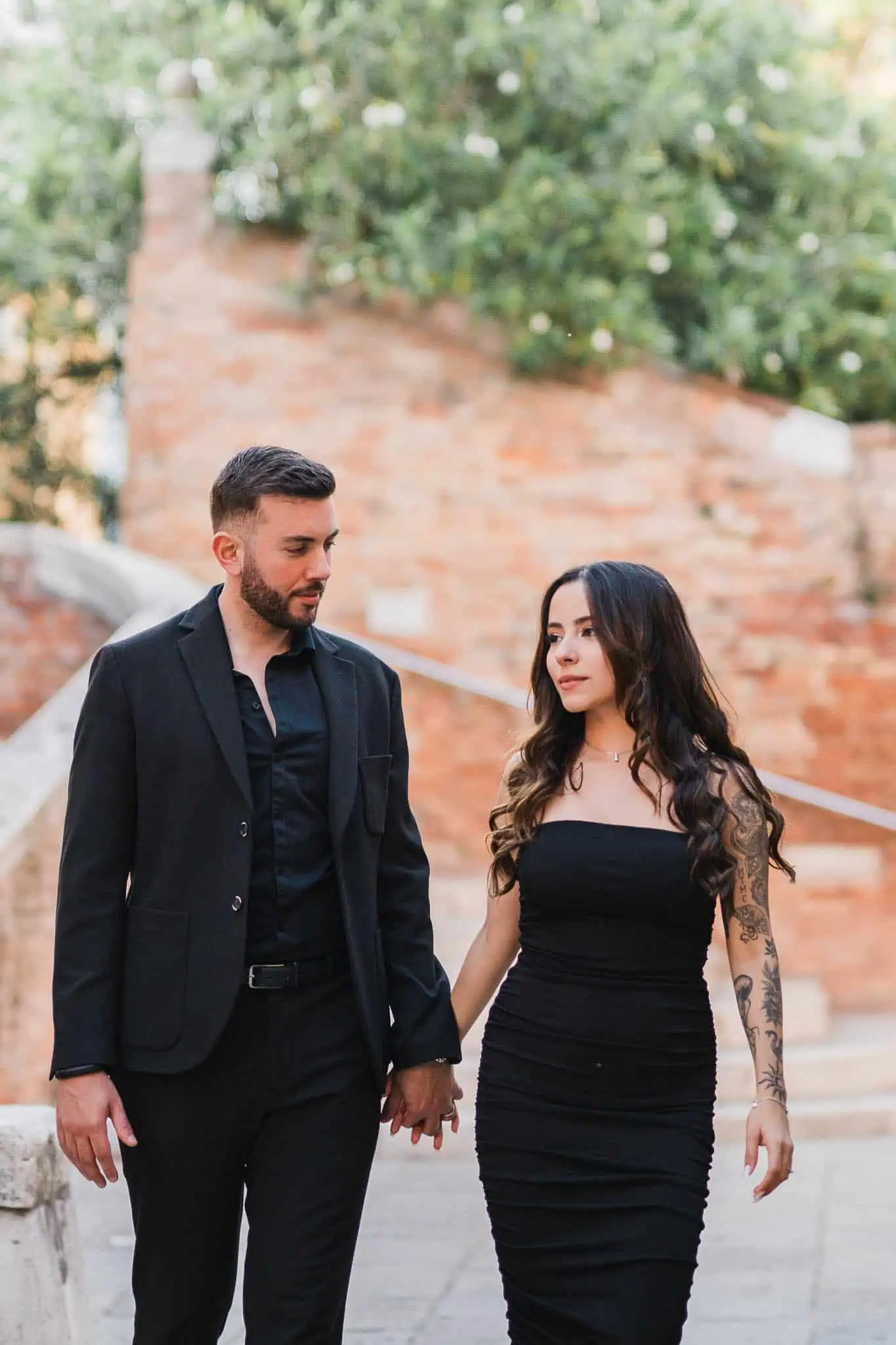 1. Romantic couple walking in Venice for engagement photoshoot, black attire, historic background.