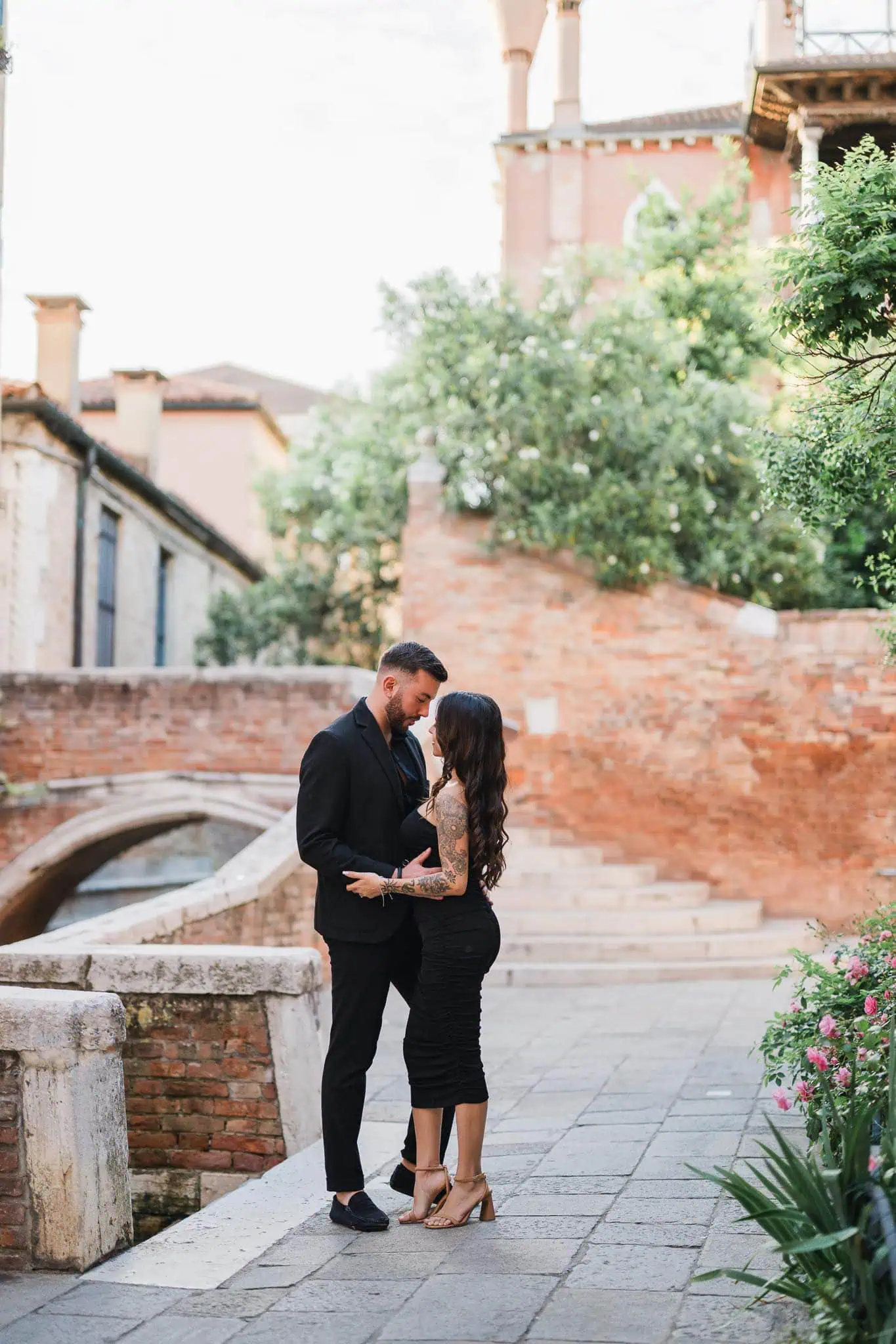 Romantic Venice engagement photo of a couple with tattoos and stylish outfits by a canal.