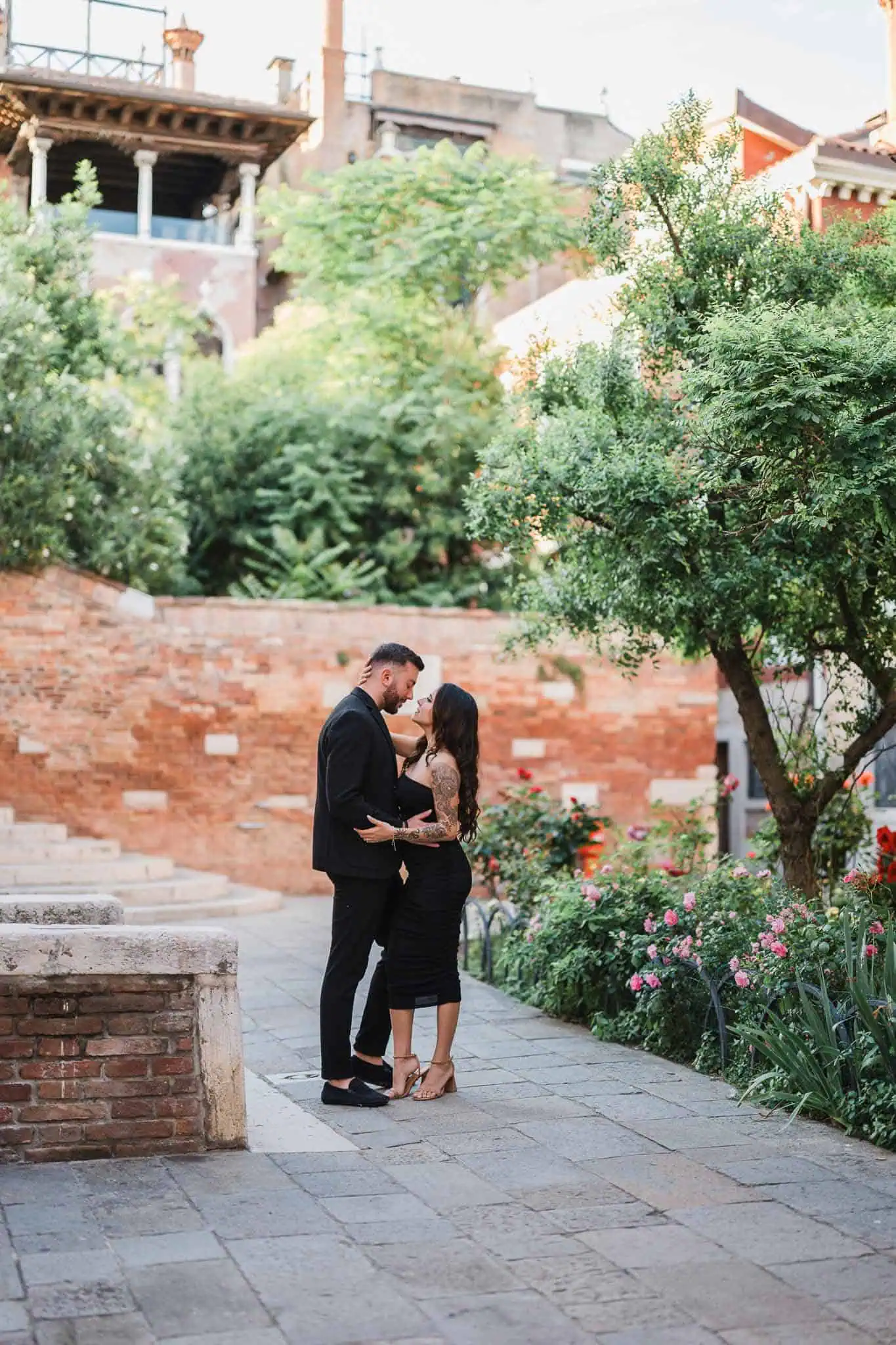 Romantic couple in Venice garden, engagement photo, colorful flowers, lush greenery, love story, picturesque setting, Venice photography, proposal moments.