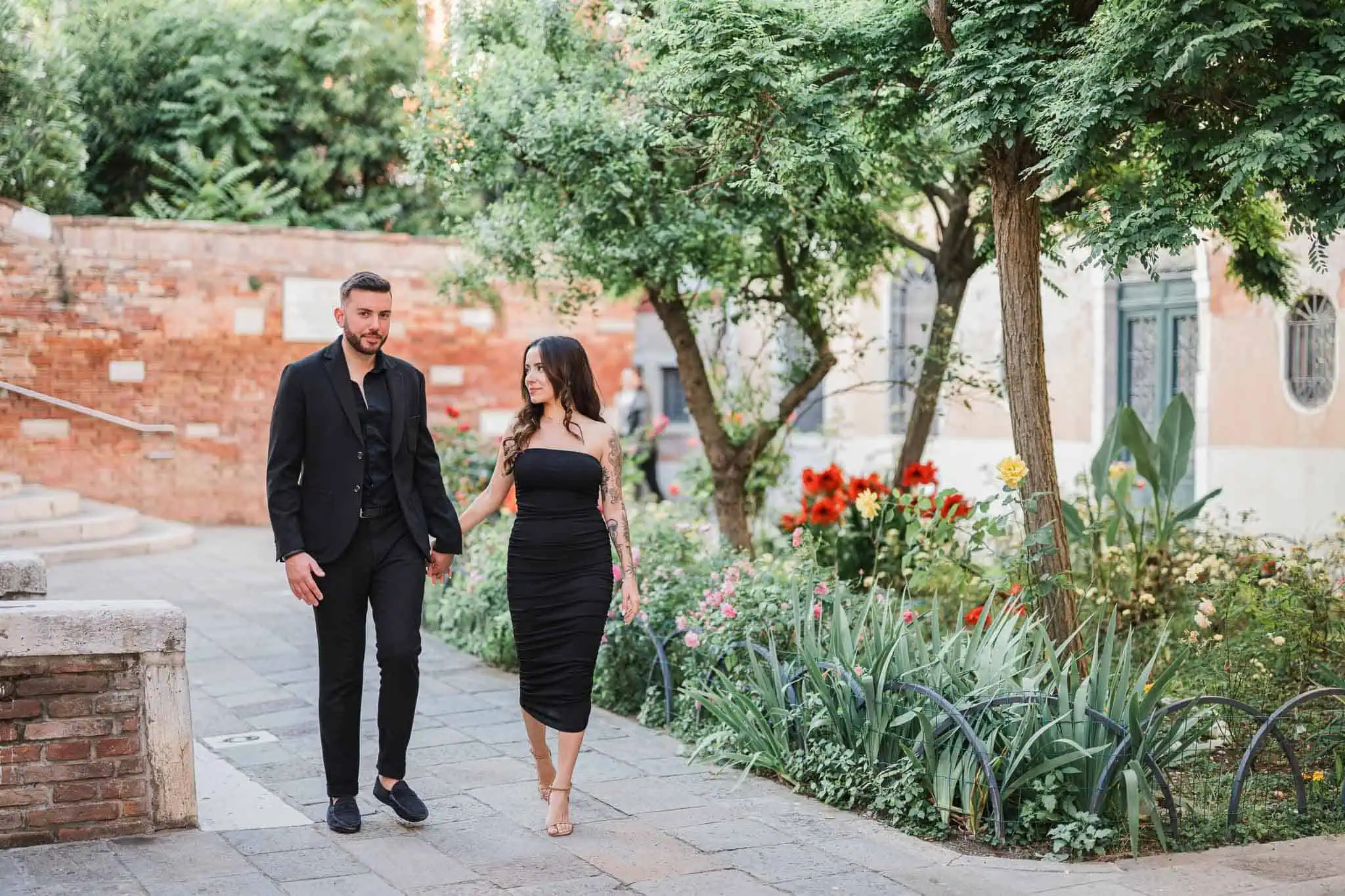 Romantic couple walking in Venice, perfect engagement photo shoot under lush green trees.