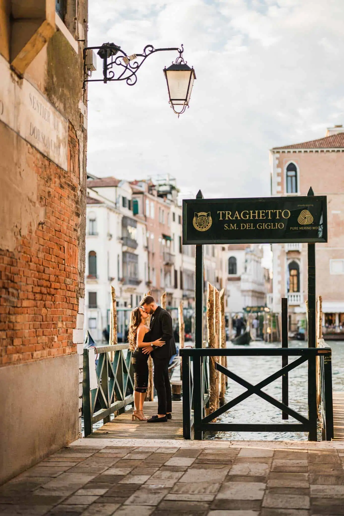 Romantic couple on Venice canal dock at sunset.
