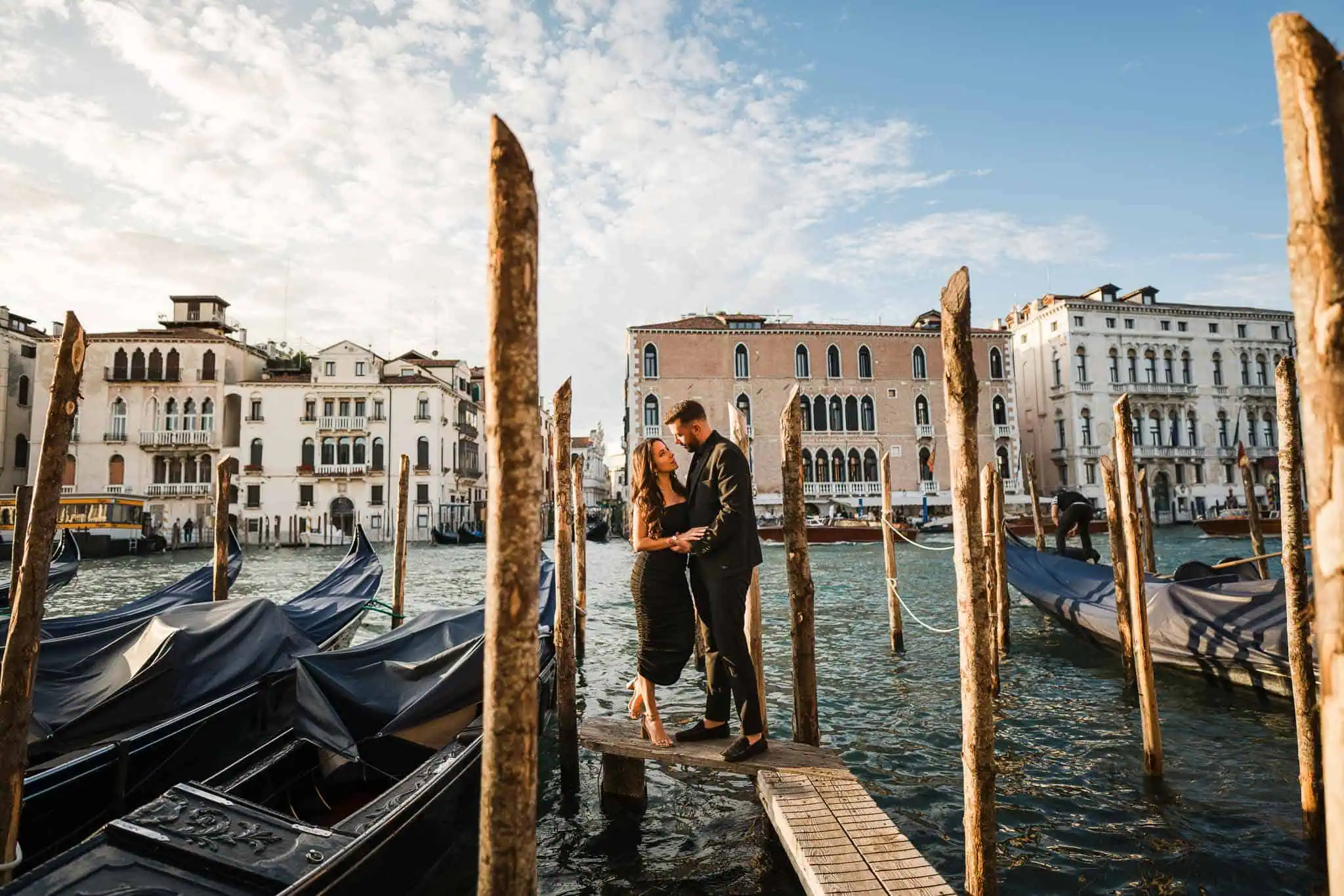 Romantic couple on gondola dock in Venice, Italy, during sunset.