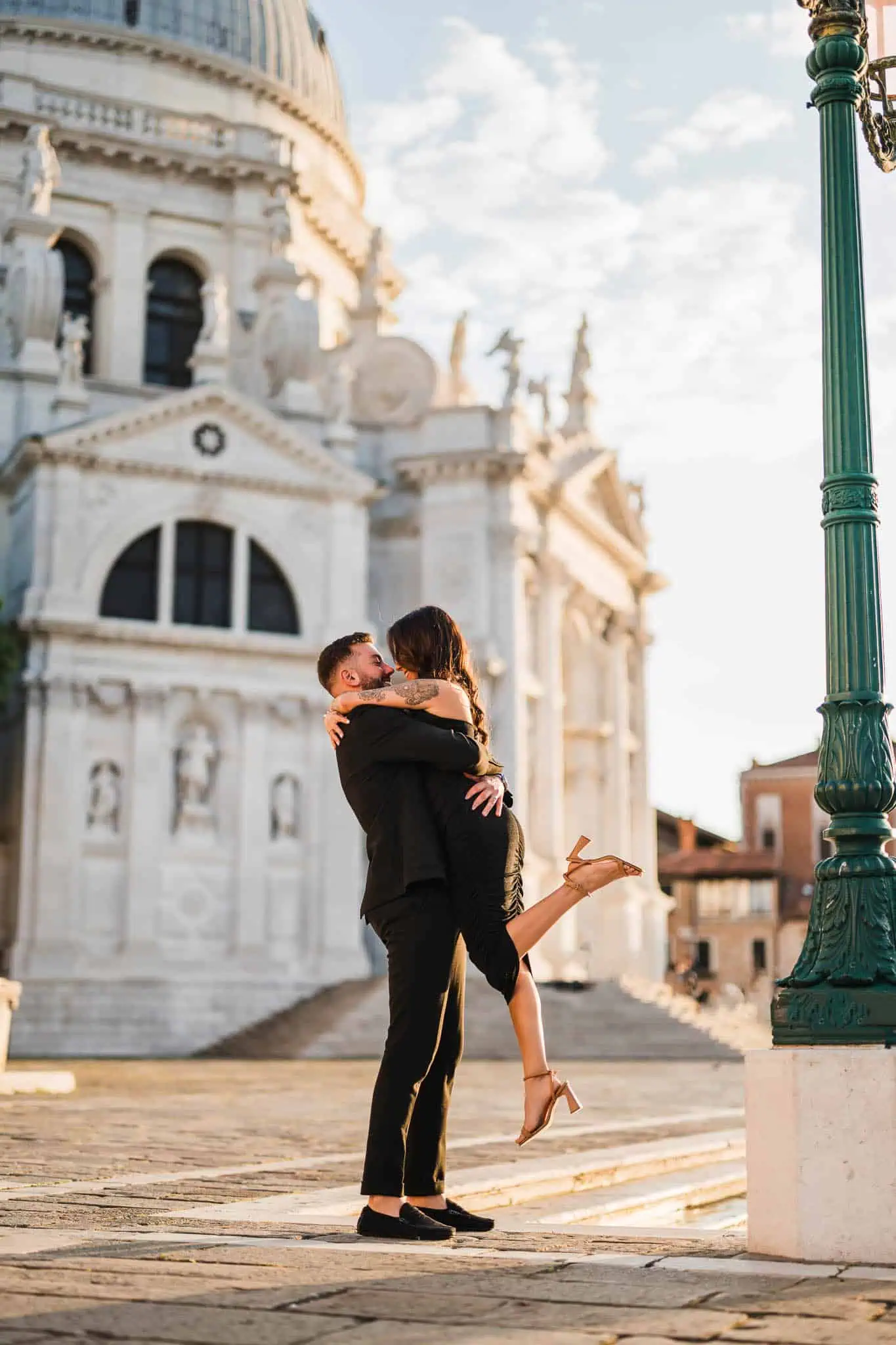 1. Joyful couple embracing in Venice with iconic church in background.