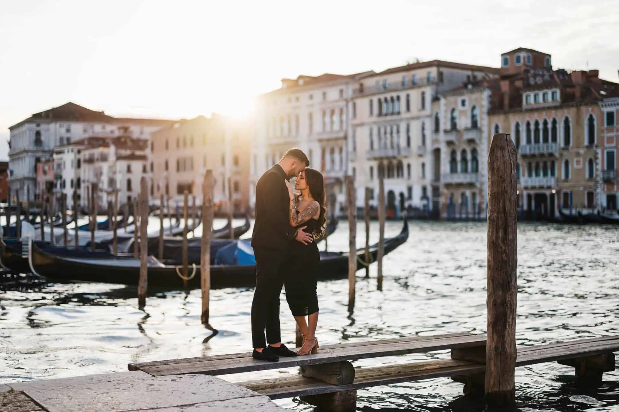 Romantic couple in Venice at sunset, engagement on a wooden dock overlooking canals.