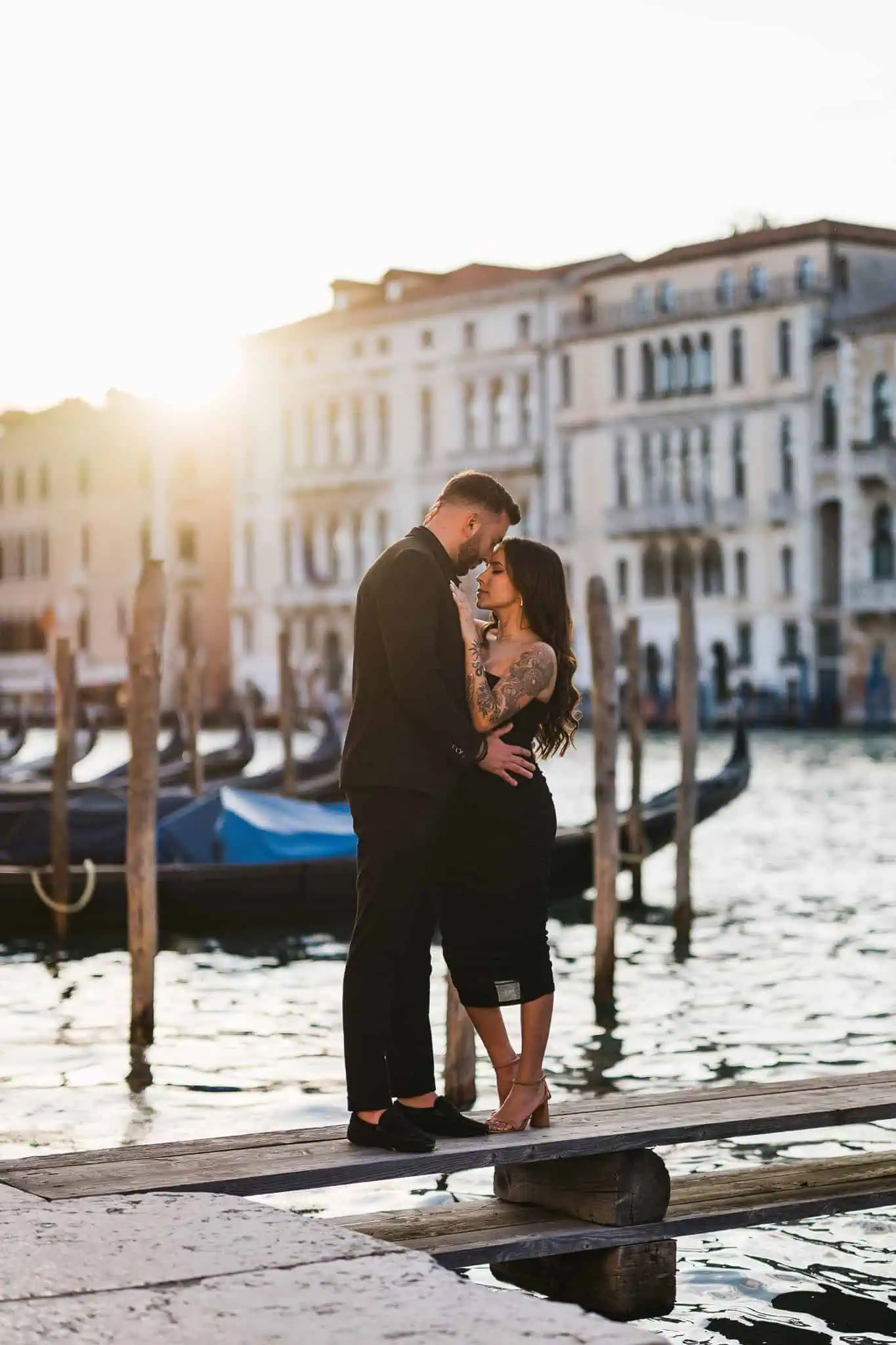 Romantic couple embracing on Venice canal at sunset for engagement photoshoot.