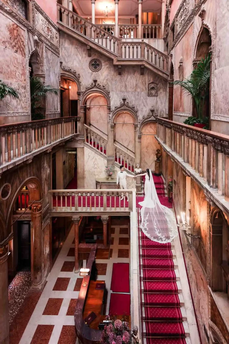 Elegant Venetian staircase at wedding venue capturing romantic moment of bride and groom.